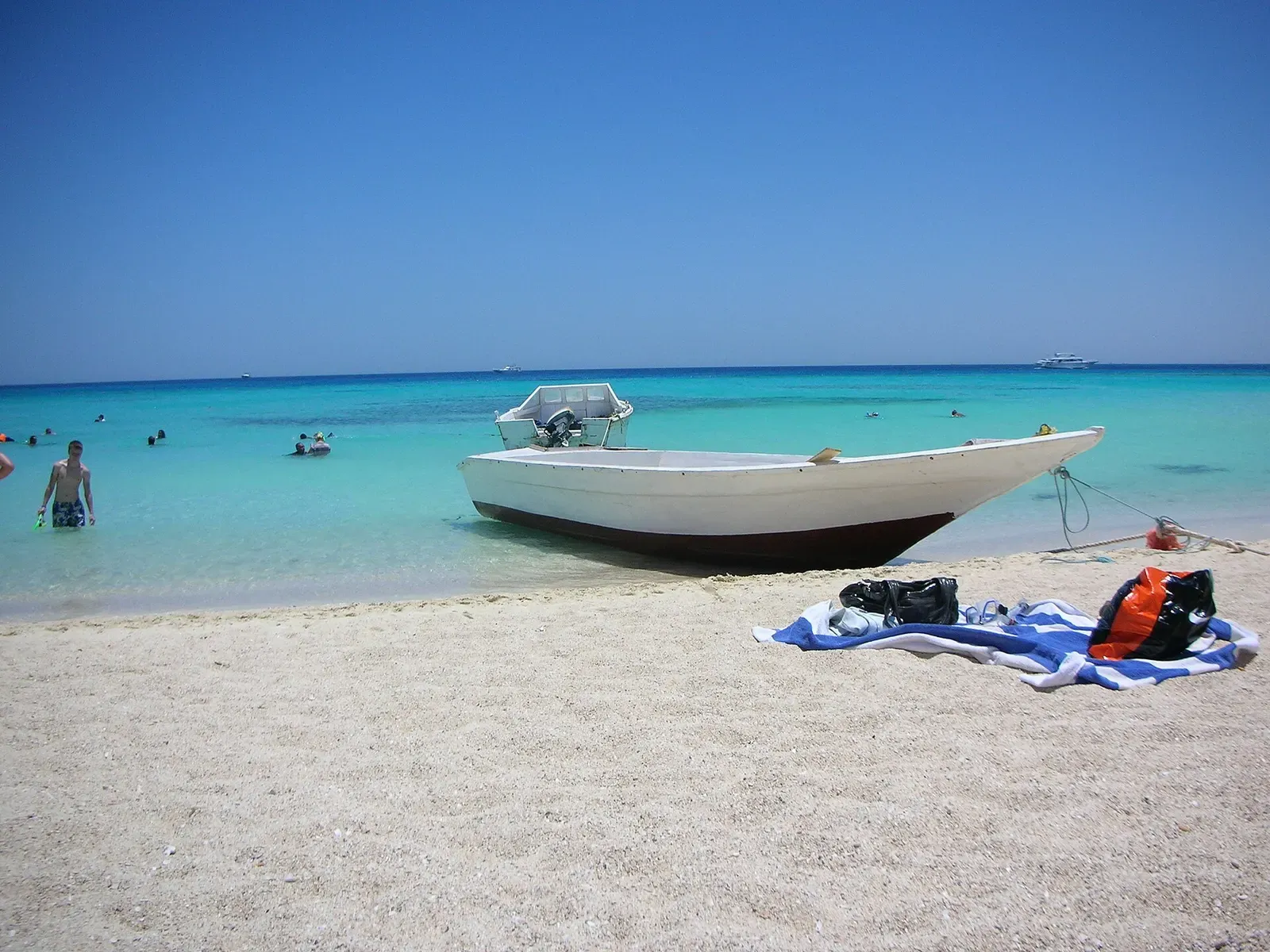 A white dive boat anchored off a sandy beach with snorkel gear laid out — Giftun Islands, Hurghada & El Gouna