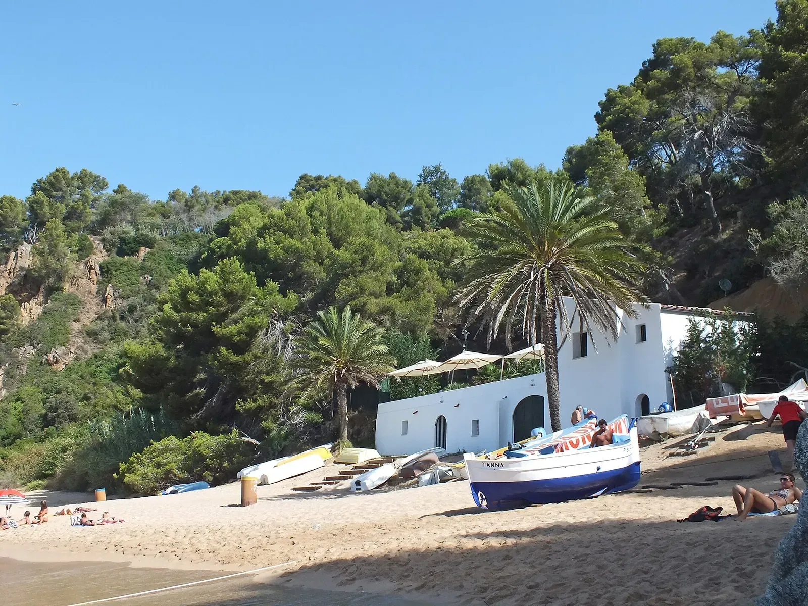 Whitewashed boathouse and beached rowing boats on the sand at Cala Canyelles.