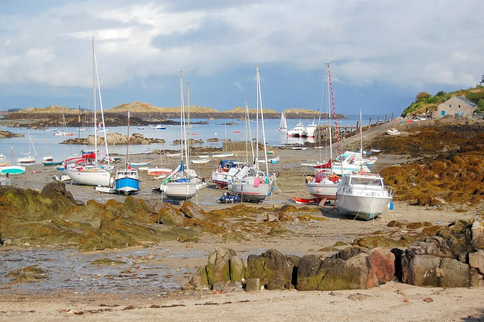 Sailing yachts stranded on rock and sand at low tide, with low islets on the horizon — Chausey Islands & Granville