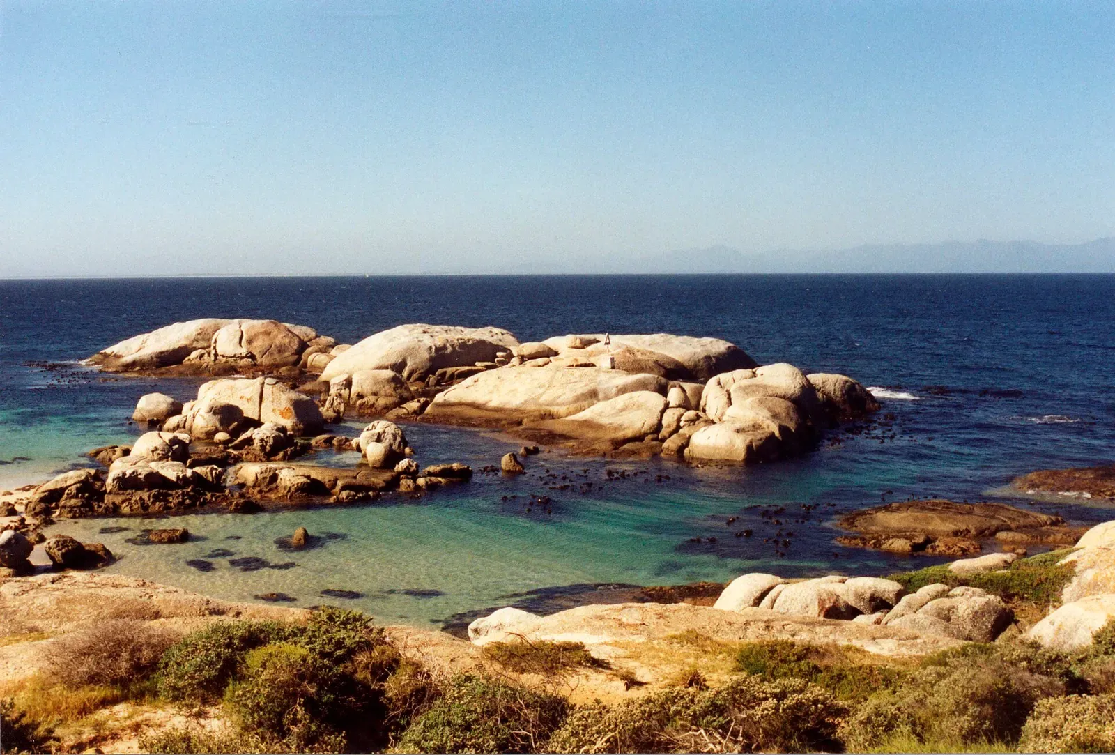 Rocky outcrops rising from calm shallow water in the east cove at Windmill Beach — Cape Town