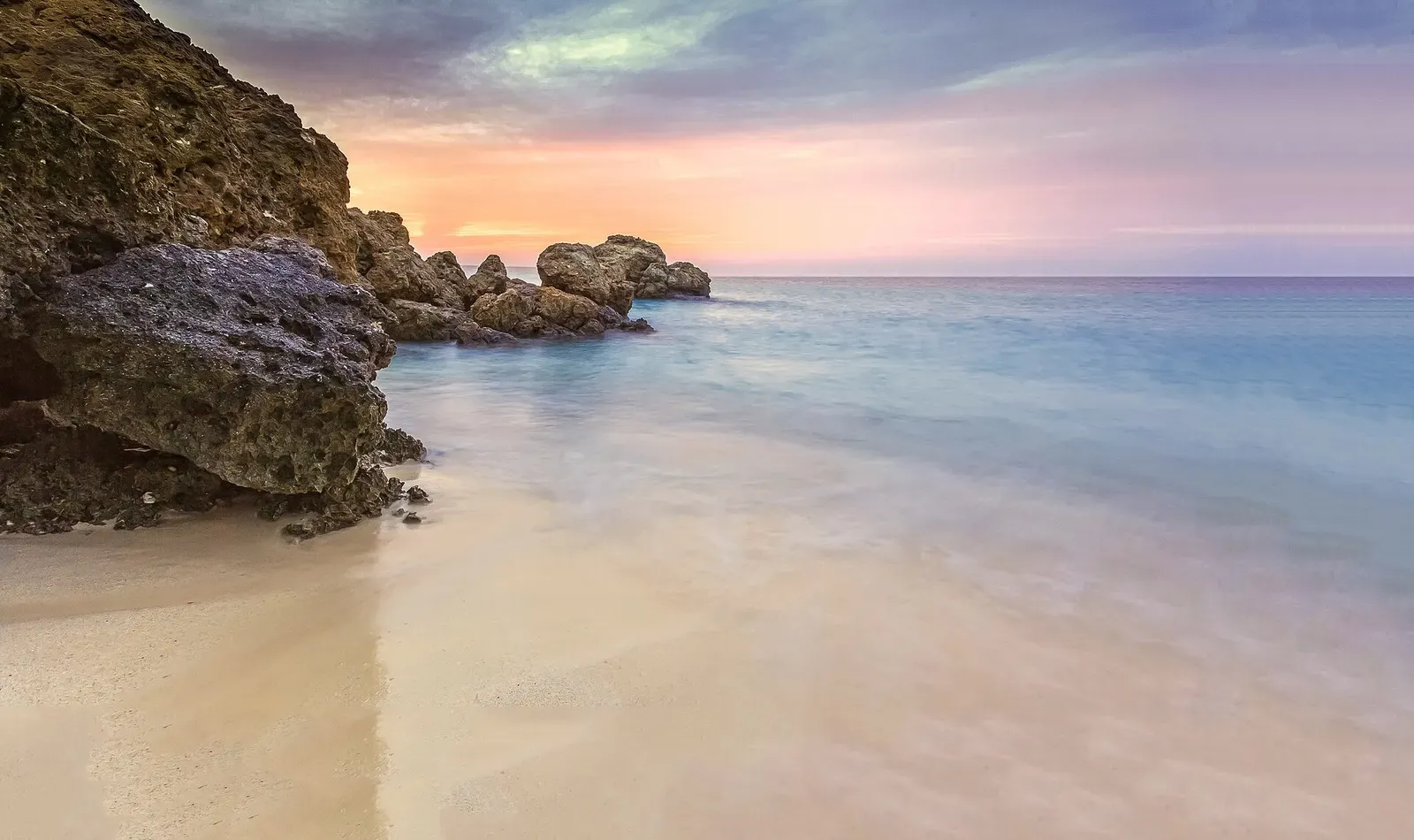 Sunset over jagged coastal rock outcrops and sand beach on Farasan Kebir — Farasan Banks