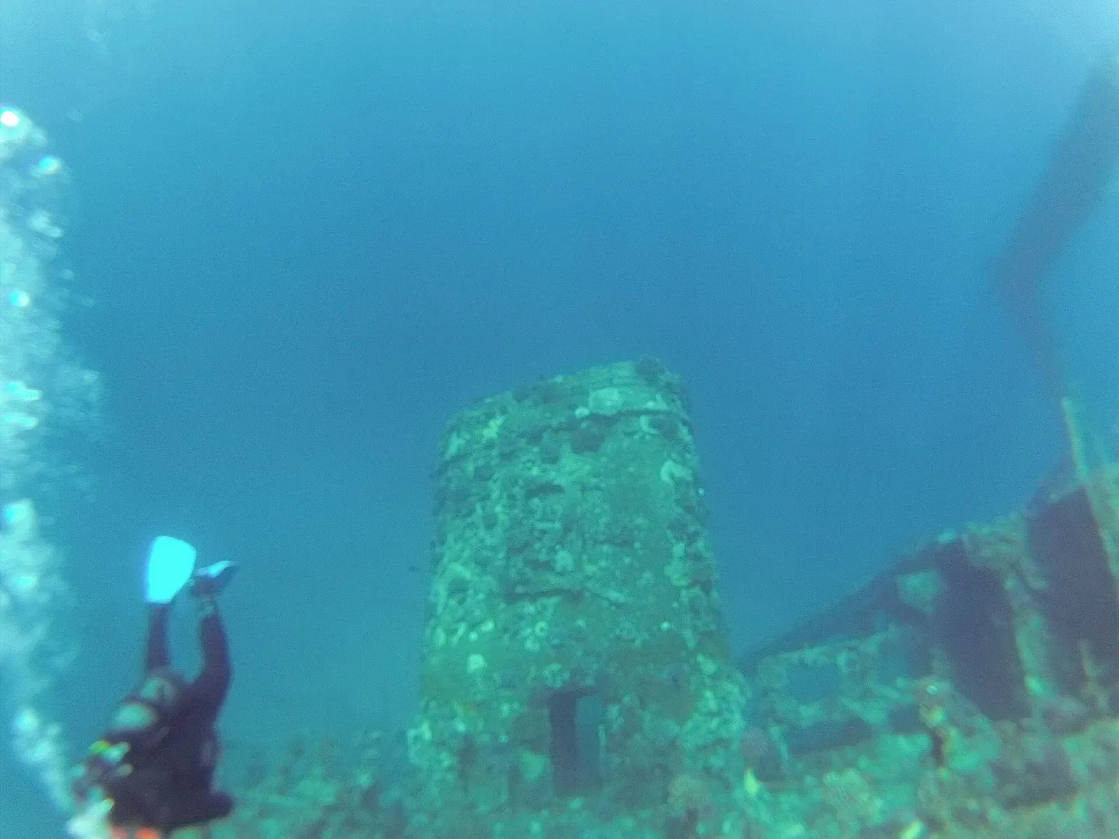 A diver with a torch beside the coral-covered funnel of the Giannis D — Hurghada & El Gouna
