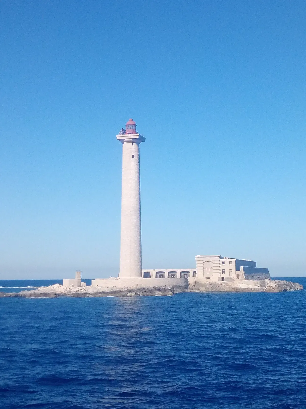 The rocky Île de Planier seen from the sea, with its lighthouse and abandoned harbour buildings — Le Planier, Marseille