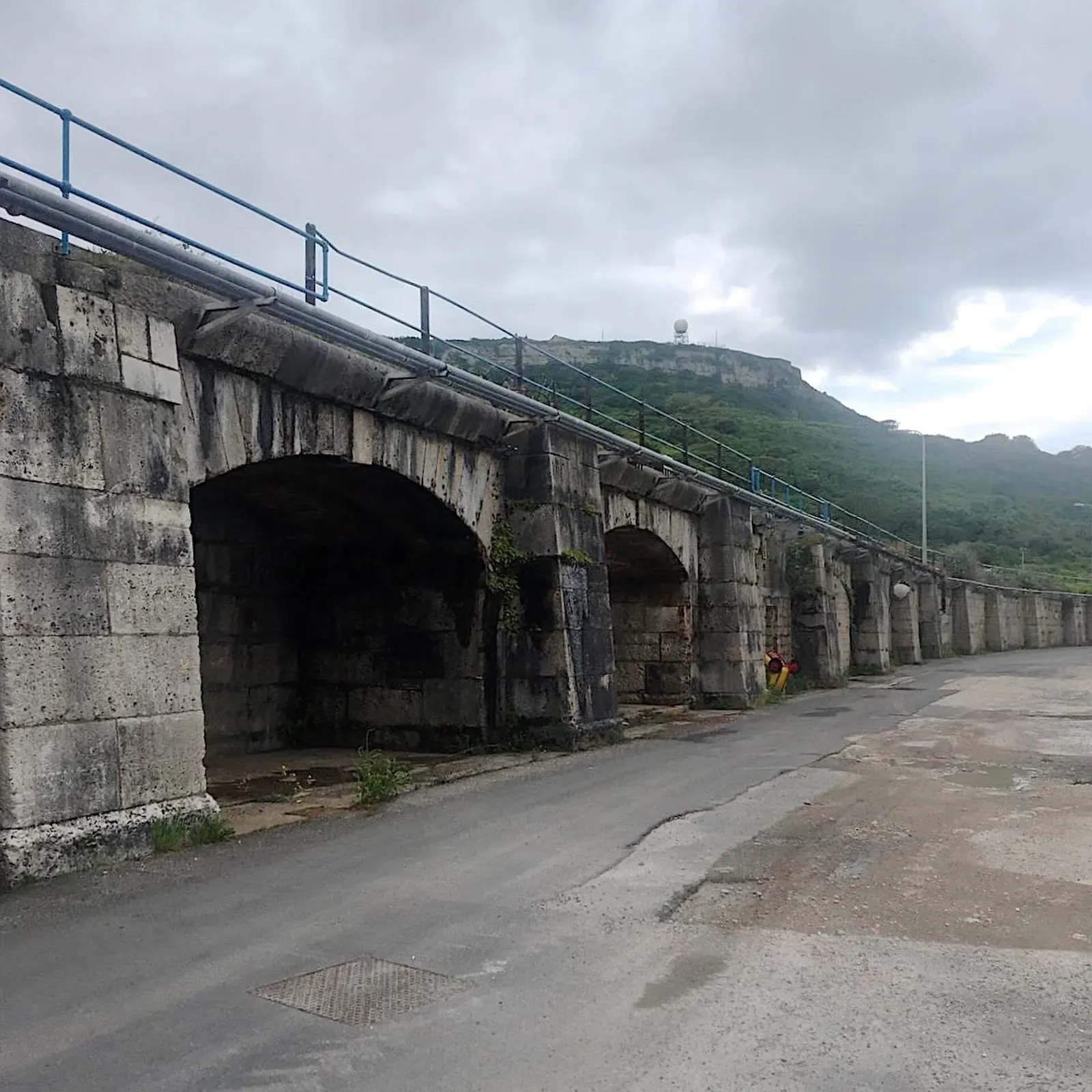 Stone arches along the Inner Breakwater at Portland Harbour, with a hillside behind
