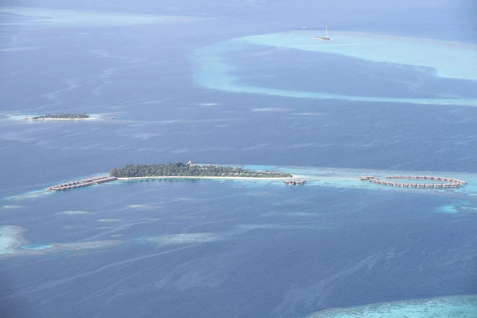 Aerial view of a small resort island on a ring reef in North Malé Atoll