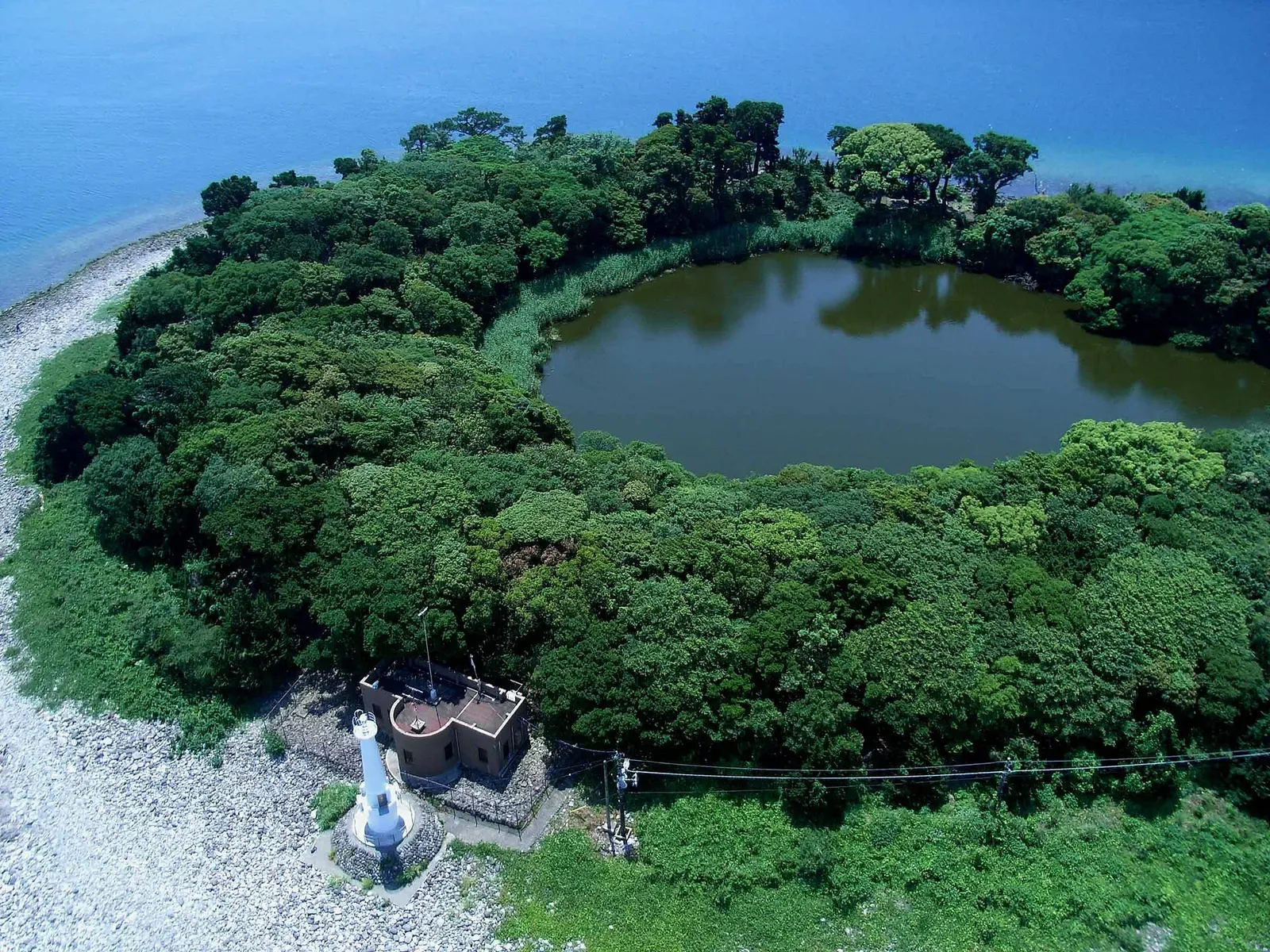 Aerial view of Kami-ike, the circular pond inside the wooded tip of the Osezaki peninsula, beside its lighthouse — Osezaki Bay