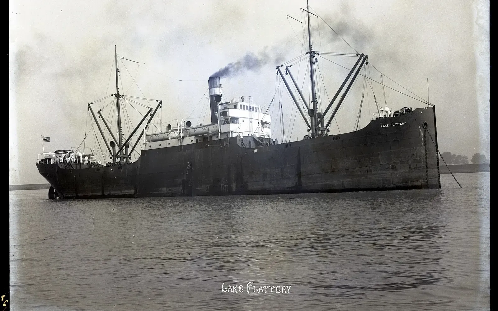 Archival black-and-white photo of the steel-hulled freighter Lake Flattery at anchor, smoke rising from her funnel — Caribsea, North Carolina Wrecks.