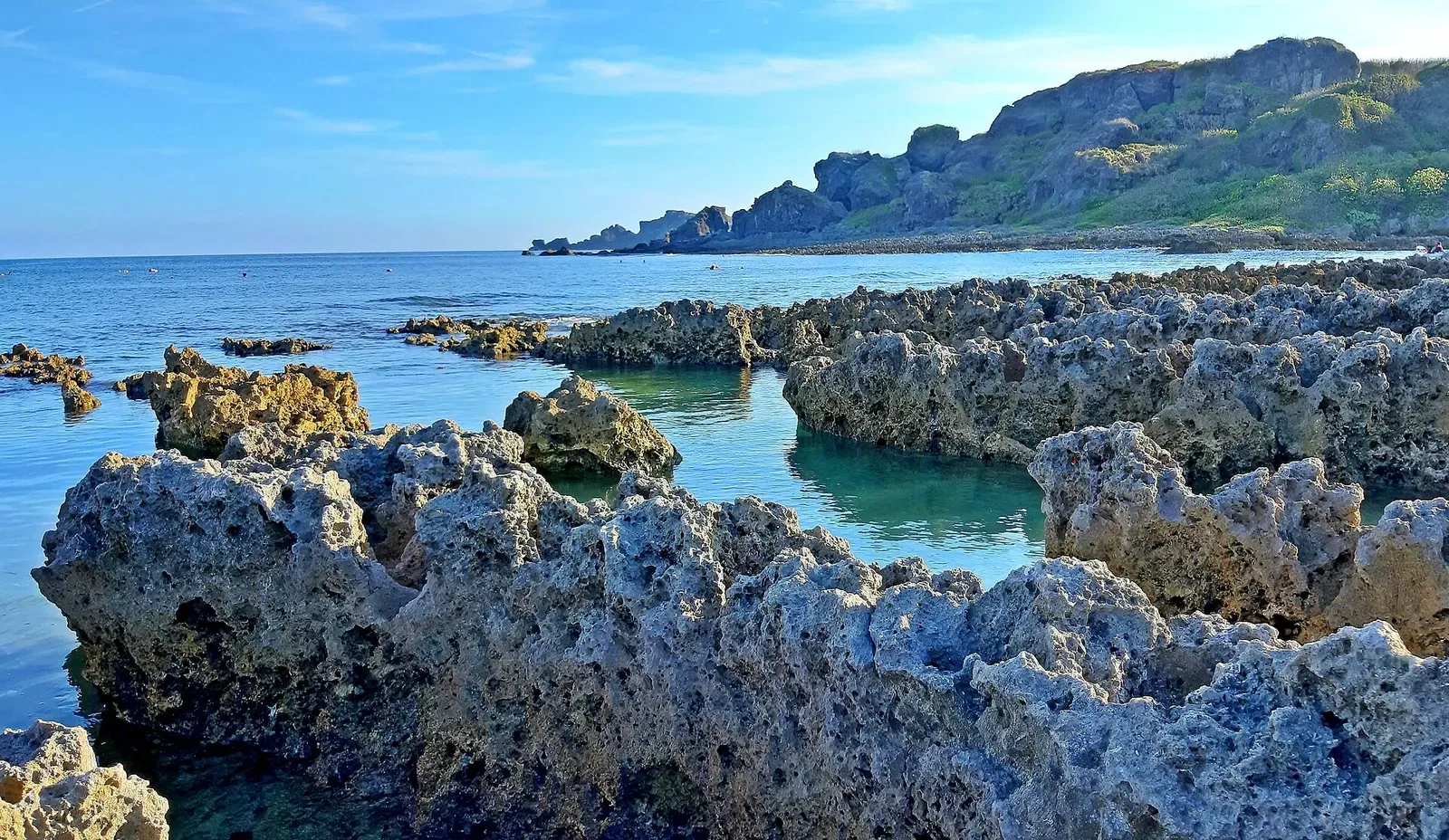 Jagged coral-rock shoreline at Little Bali Island with the Hengchun headland beyond — Kenting.