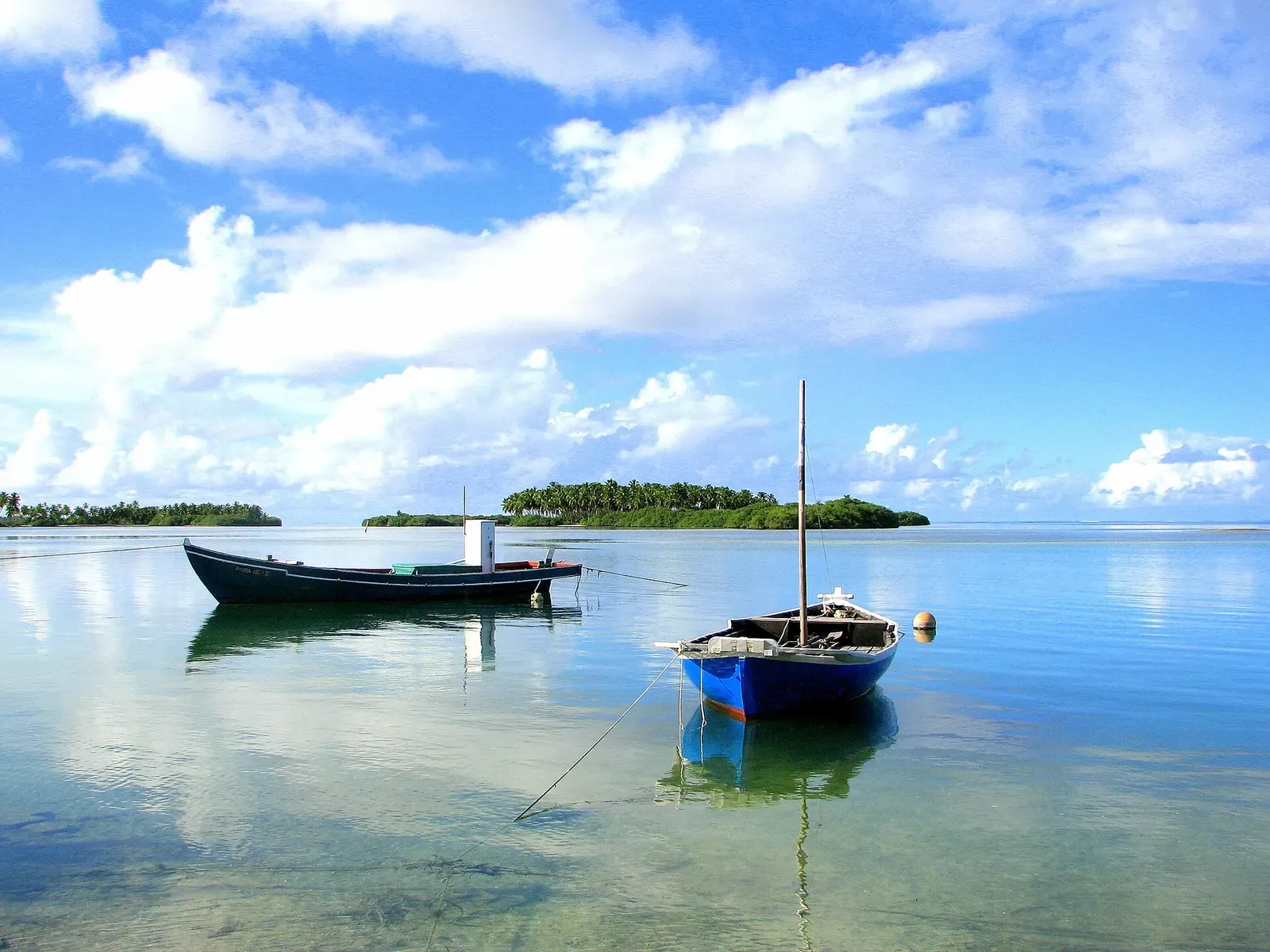 Two small wooden boats moored in shallow clear water off Hithadhoo — Addu Atoll