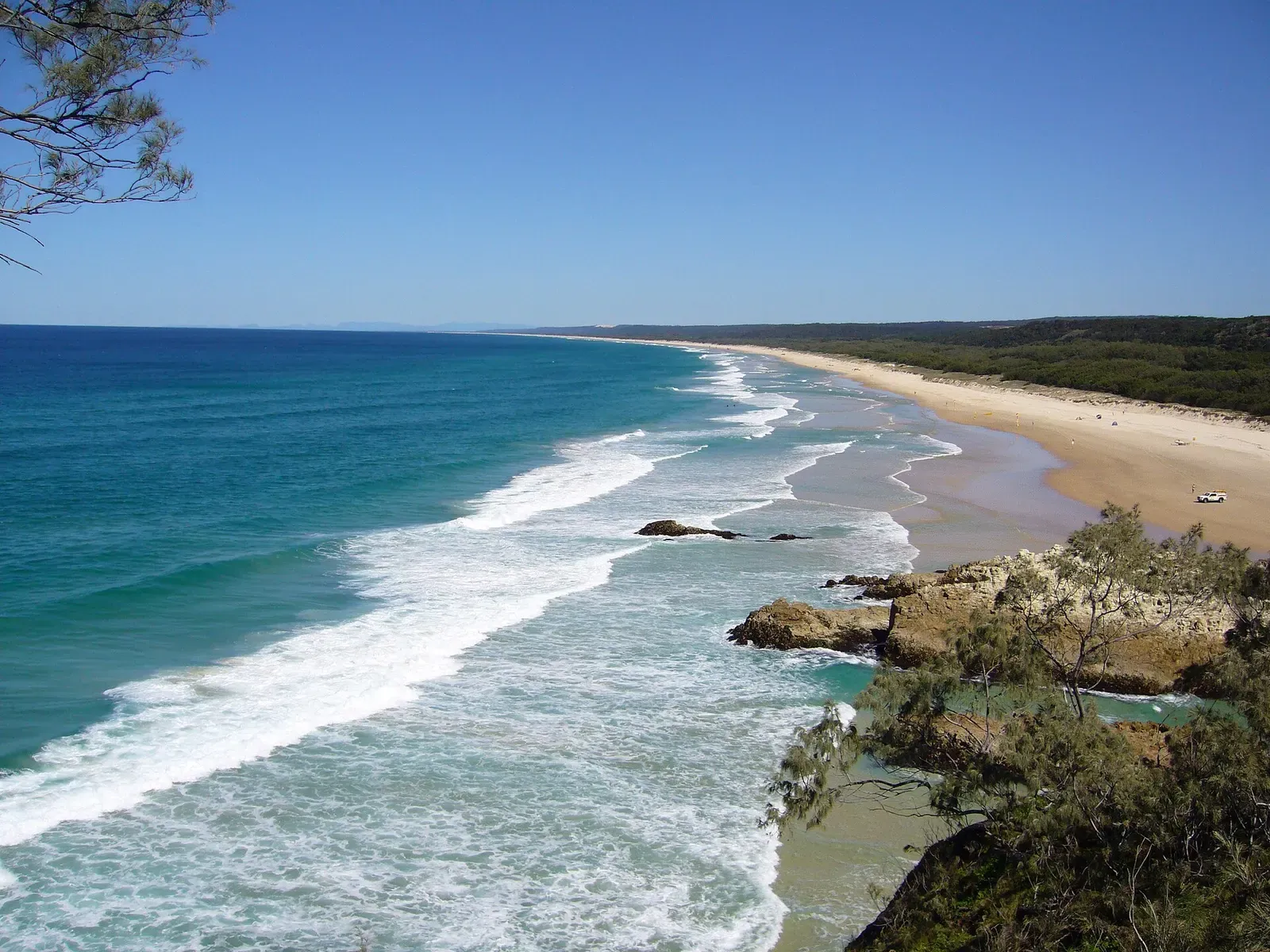 A rocky point and curving sandy beach meeting the surf at Main Beach.