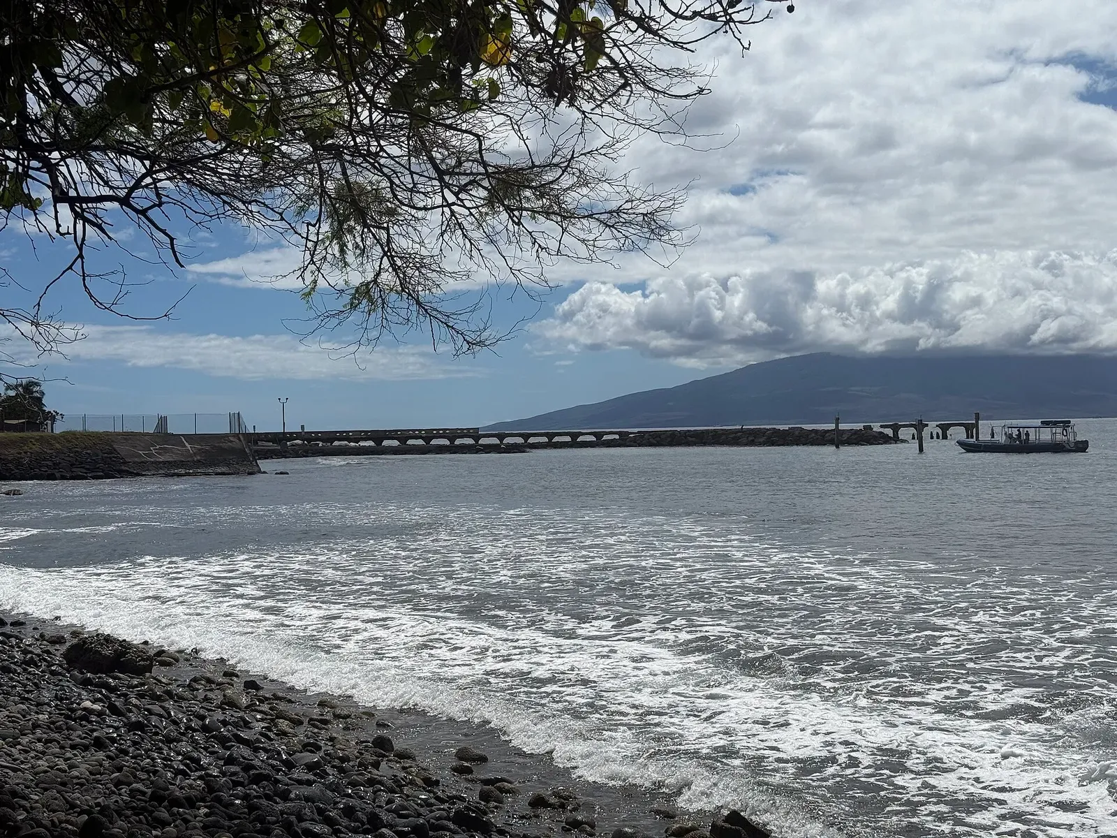 View along the broken wharf from the beach, with a dive boat moored near the far end — Mala Wharf, Maui