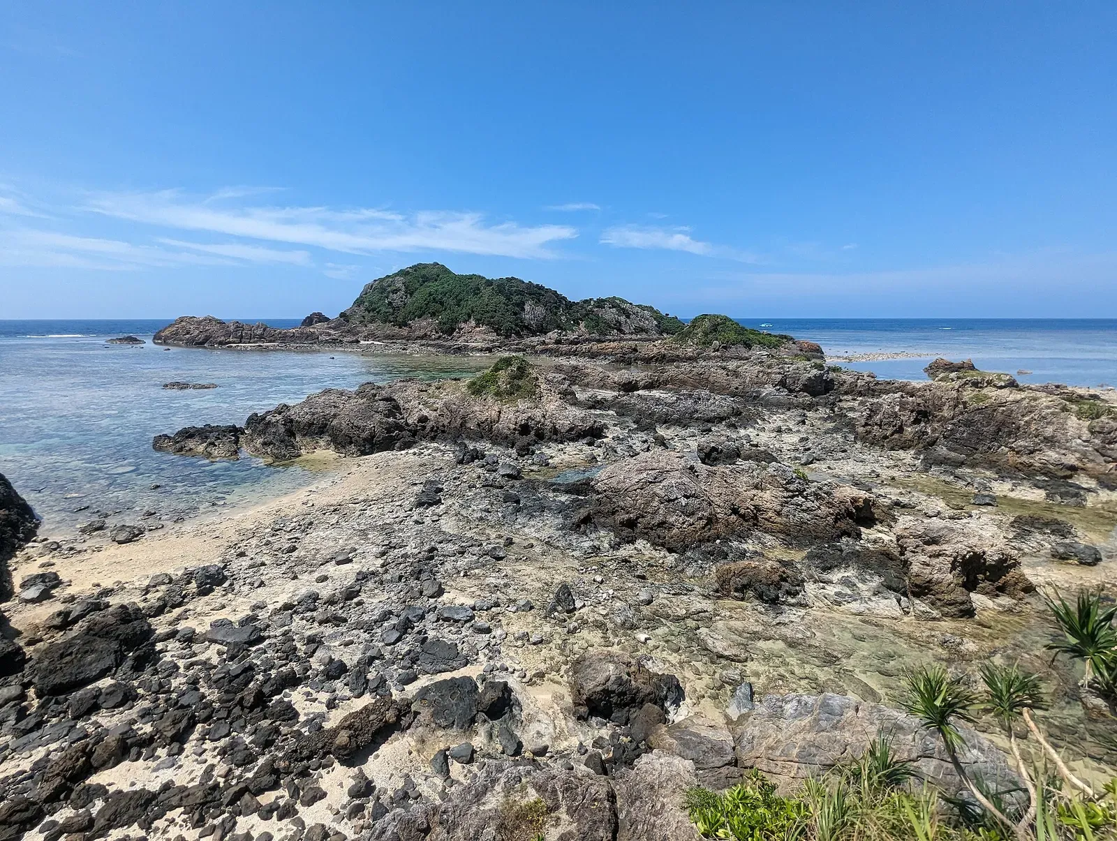 Low rocky islet surrounded by exposed reef flat and clear shallow water — Manta Scramble, Ishigaki