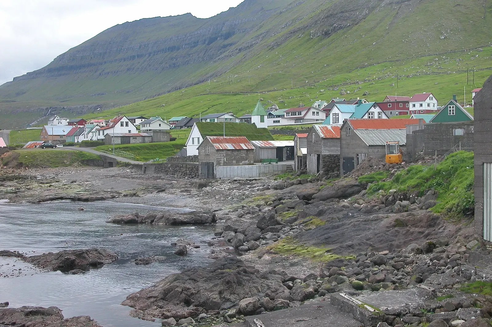 Houses at Oyndarfjørður clustered along a rocky, tide-washed shoreline — The Rocking Stones in Oyndarfjørður, Faroe Islands