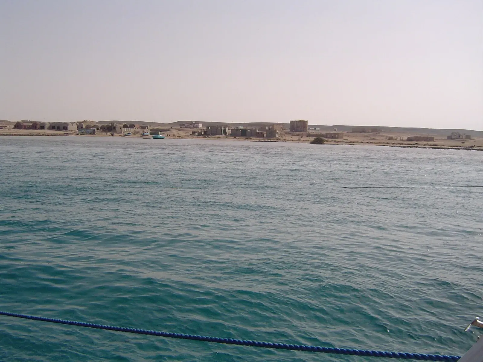 View of the shoreline and buildings at Port Hamata seen from a boat.