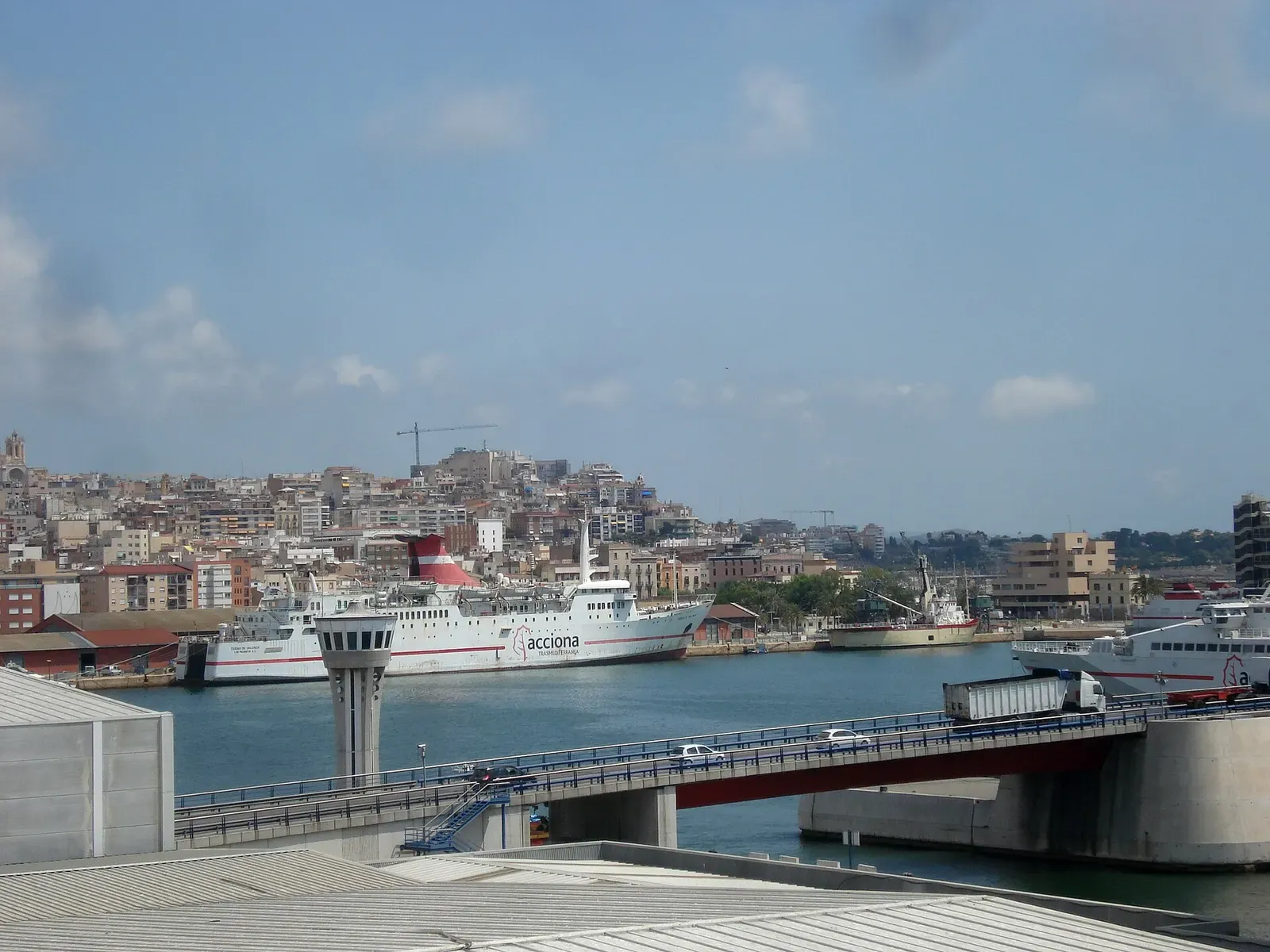 A ferry docked in the Port of Tarragona with the city skyline rising behind the harbour