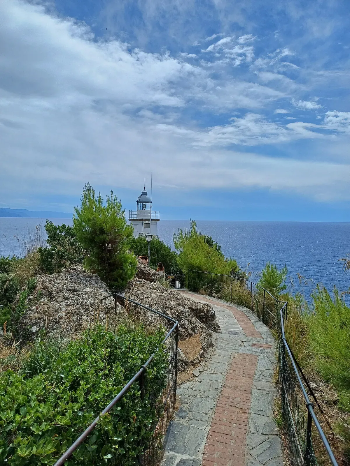 Stone path winding along the cliff edge toward the Portofino lighthouse — Punta del Faro