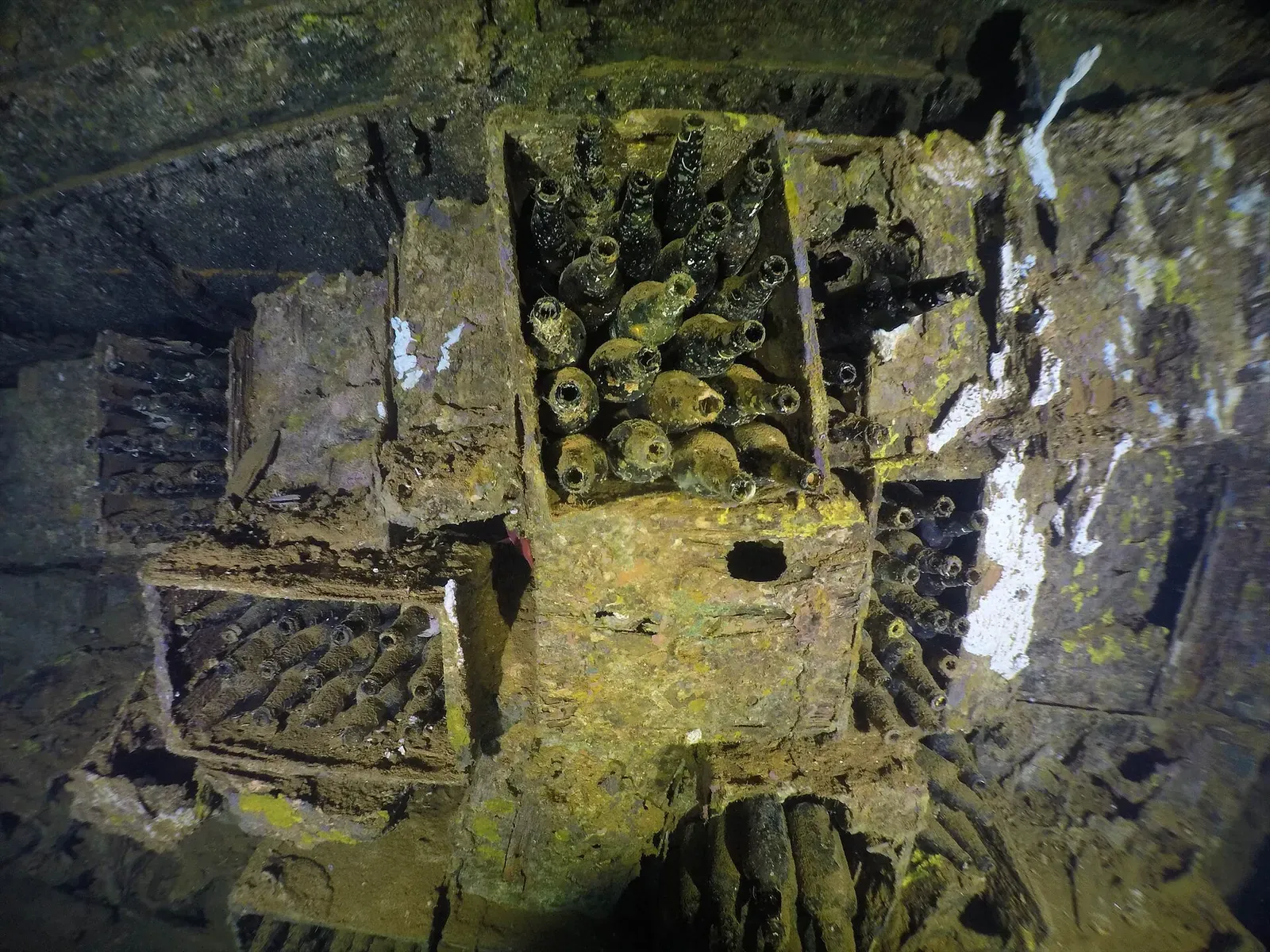 Crates of old beer bottles packed in a wreck hold, seen from above under torchlight — Rio de Janeiro Maru, Chuuk Lagoon.