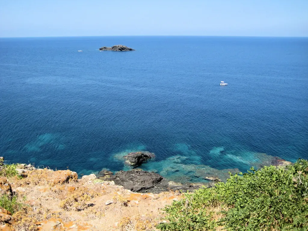 View across open water toward the small rock of Scoglio del Medico from the Ustica shoreline