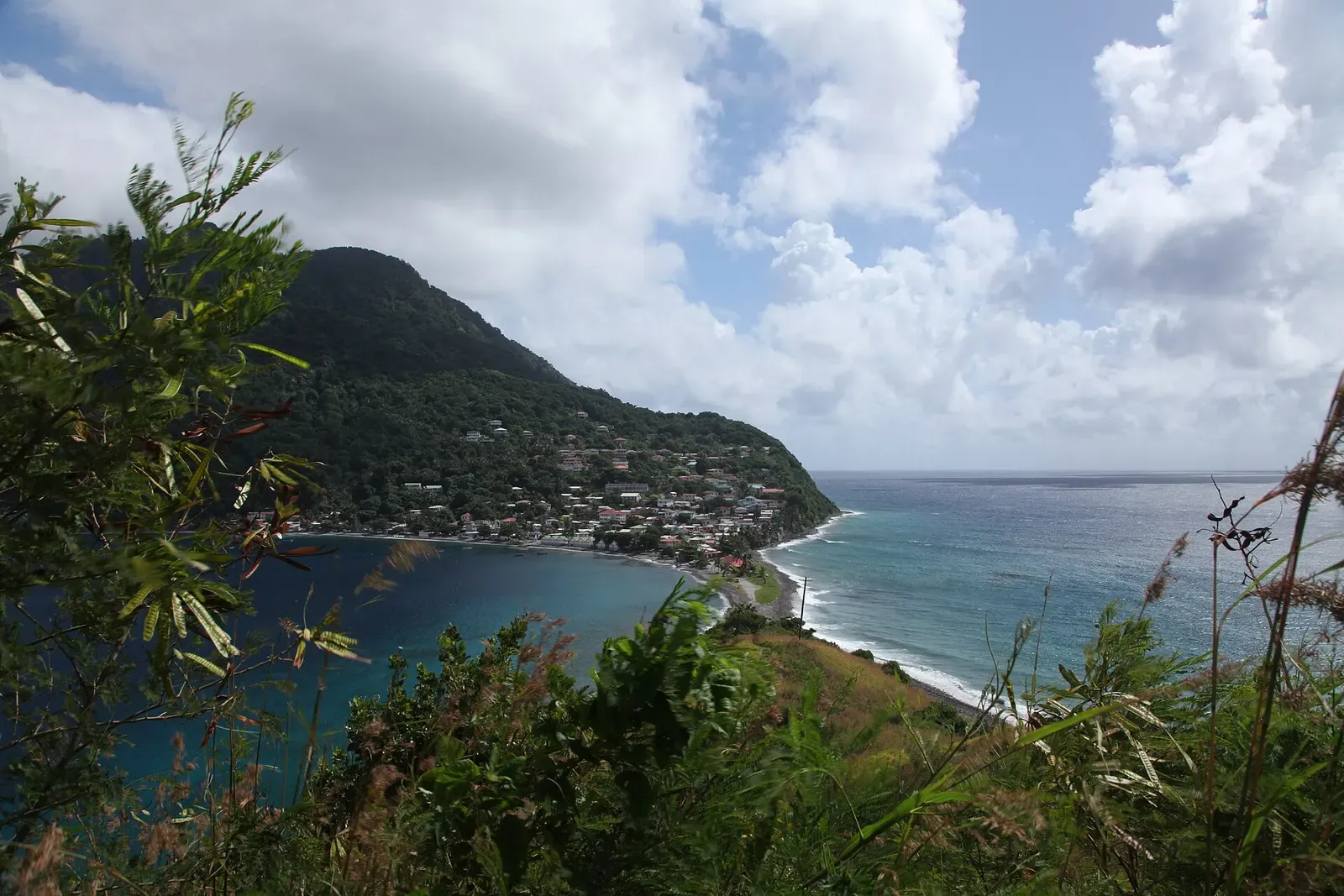 The village of Scotts Head seen from the peninsula, with the coastline curving toward the point — Scott's Head Drop-off, Dominica