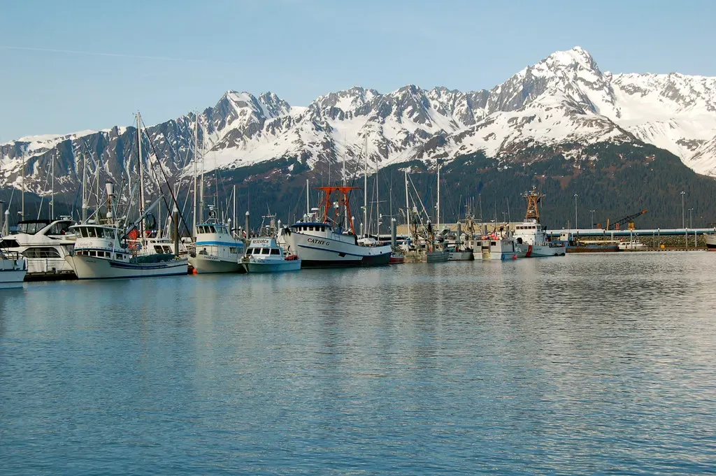 Fishing boats moored in Seward harbor below a row of snow-capped mountains