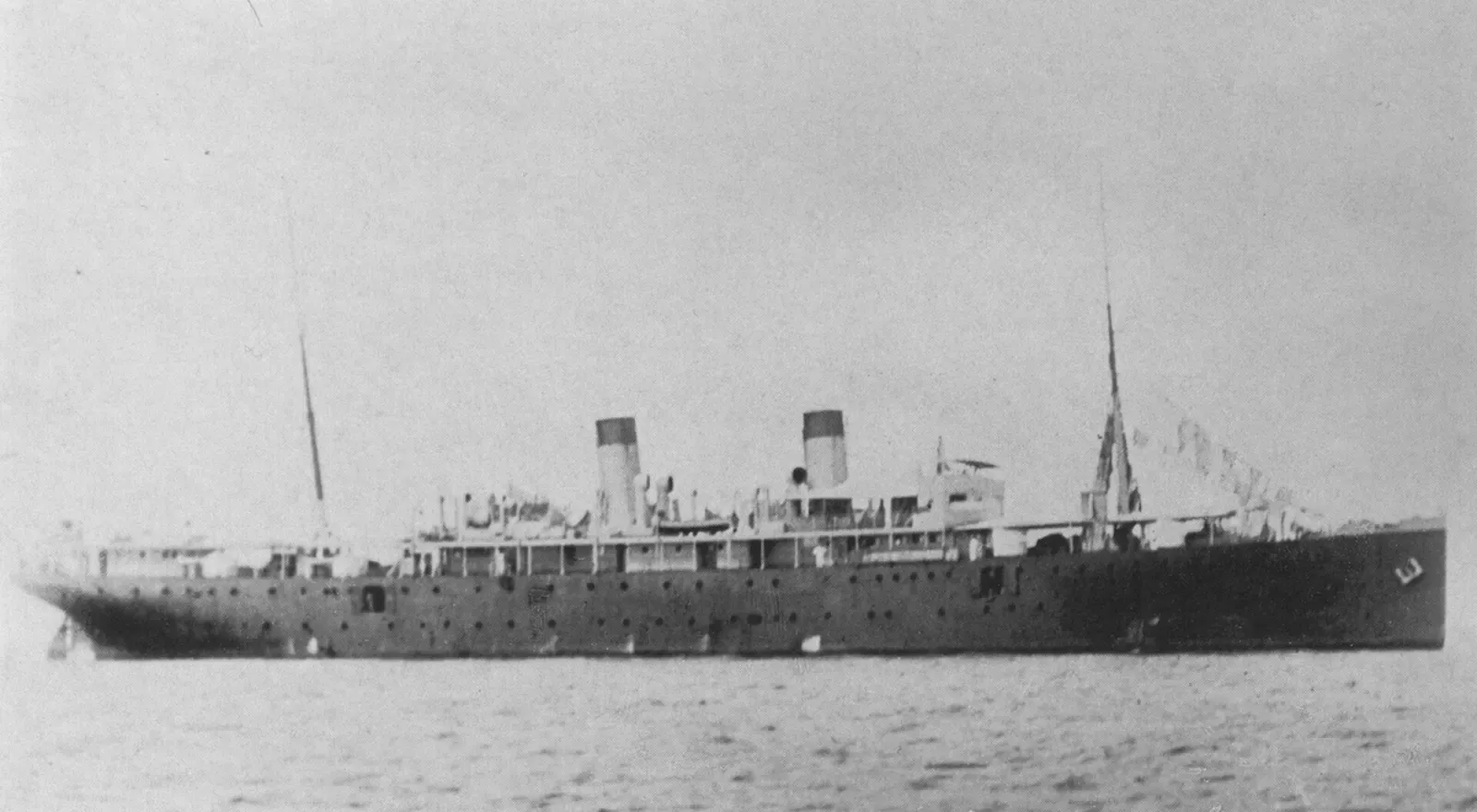 Black and white photo of the steamship SMS Cormoran afloat, twin funnels smoking — Guam