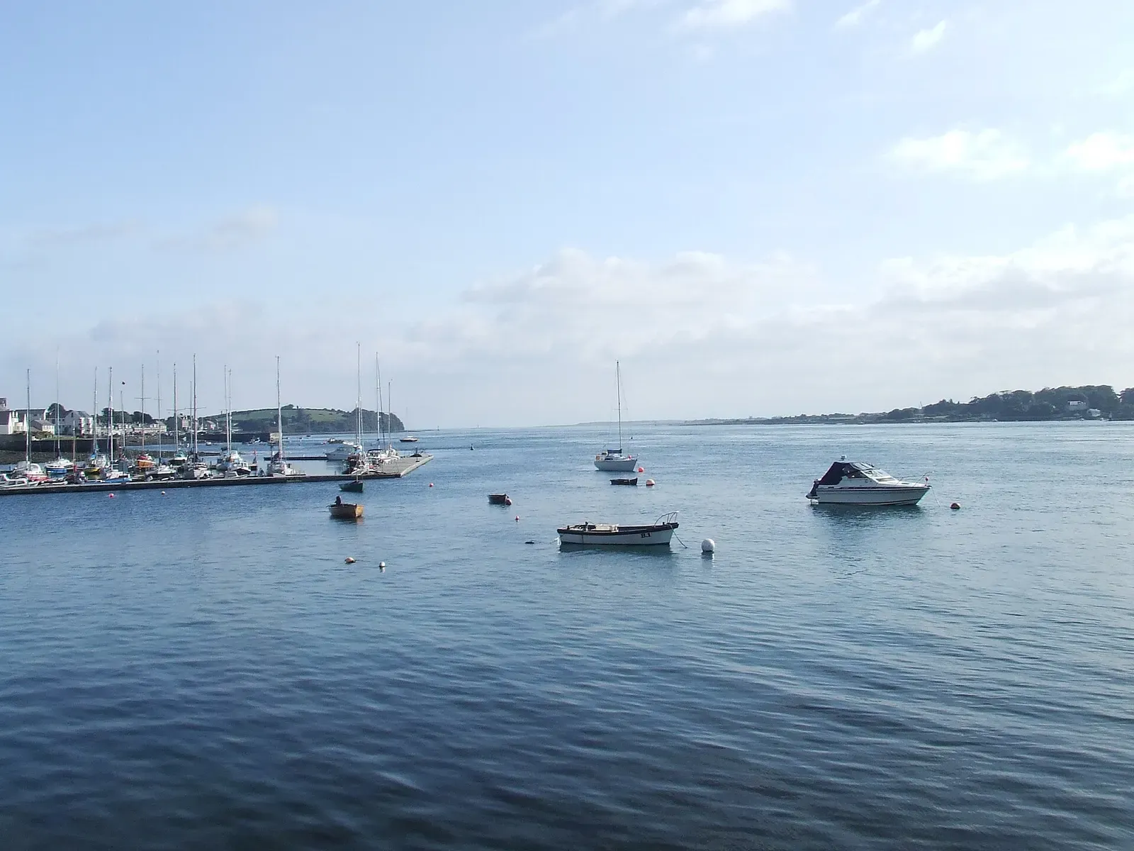 Small motorboats moored on calm blue water off a marina, with a low headland on the horizon — Strangford Lough