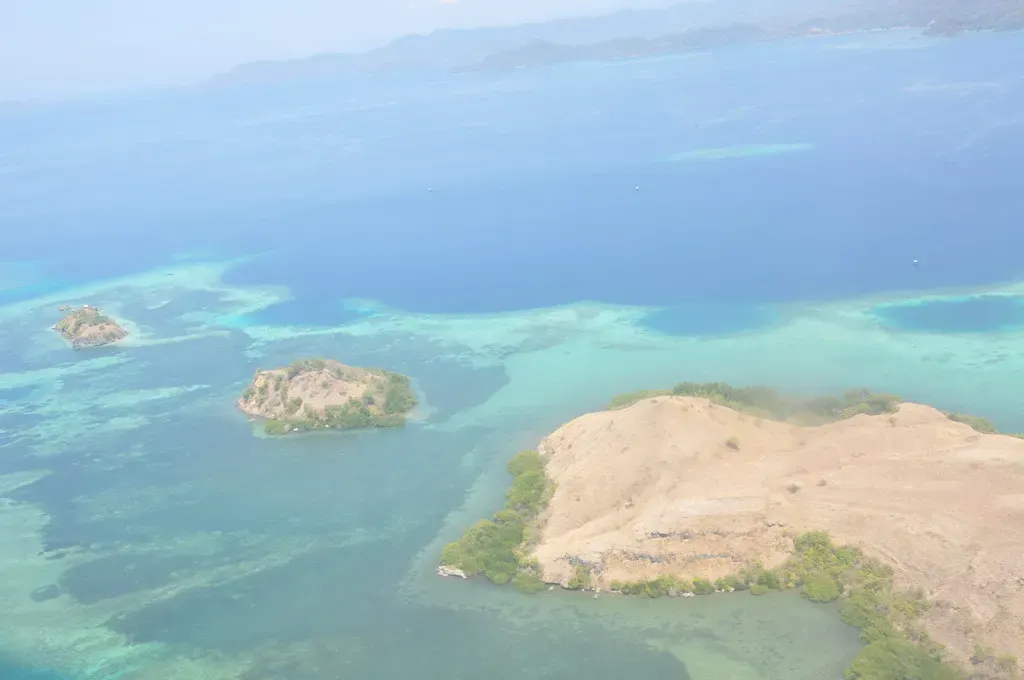 Aerial view of small sandy islets ringed by pale turquoise reef flats in a blue sea — Kepulauan Seribu (Thousand Islands)