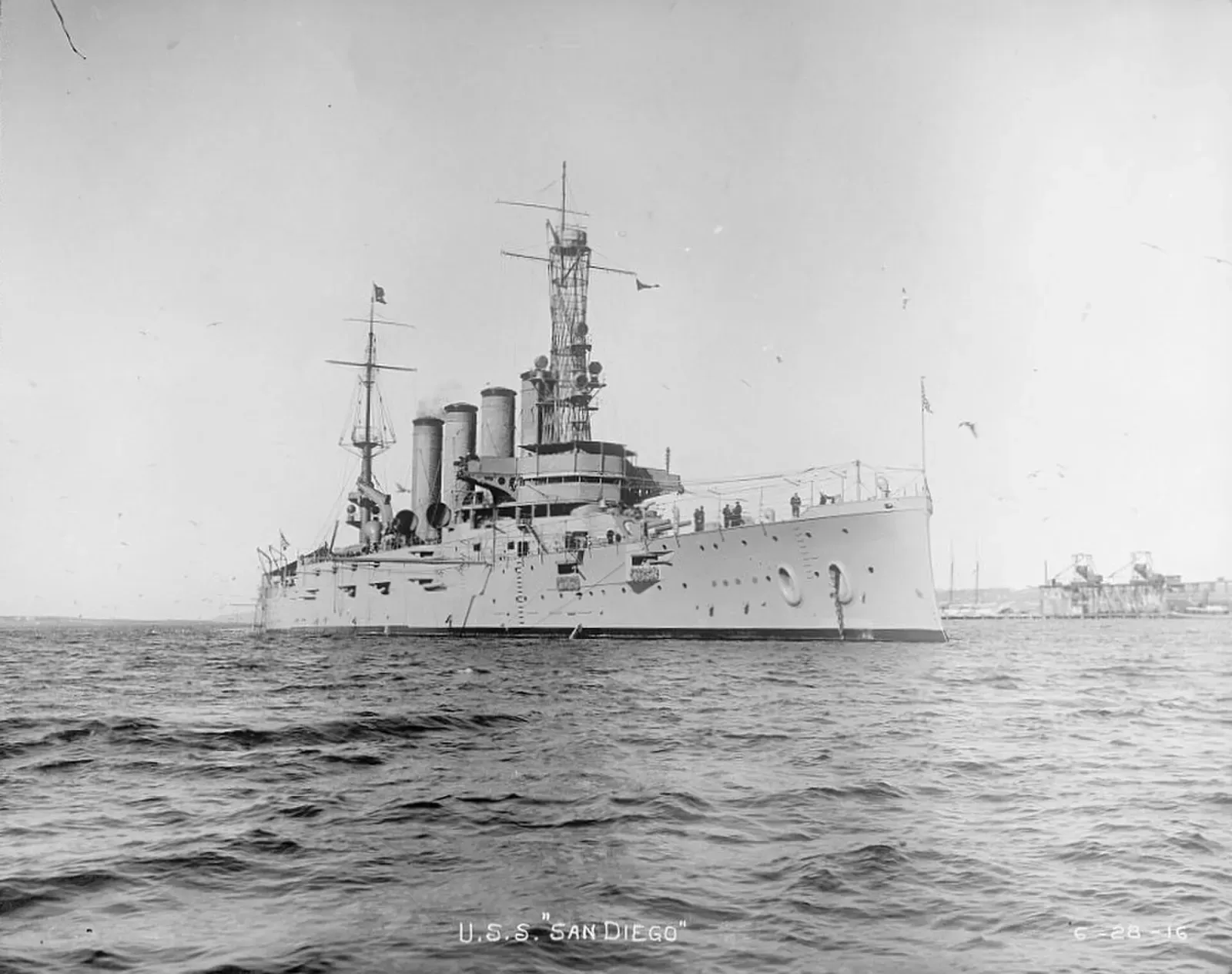 The armoured cruiser USS San Diego at anchor, her four tall funnels and cage mast visible against open water.