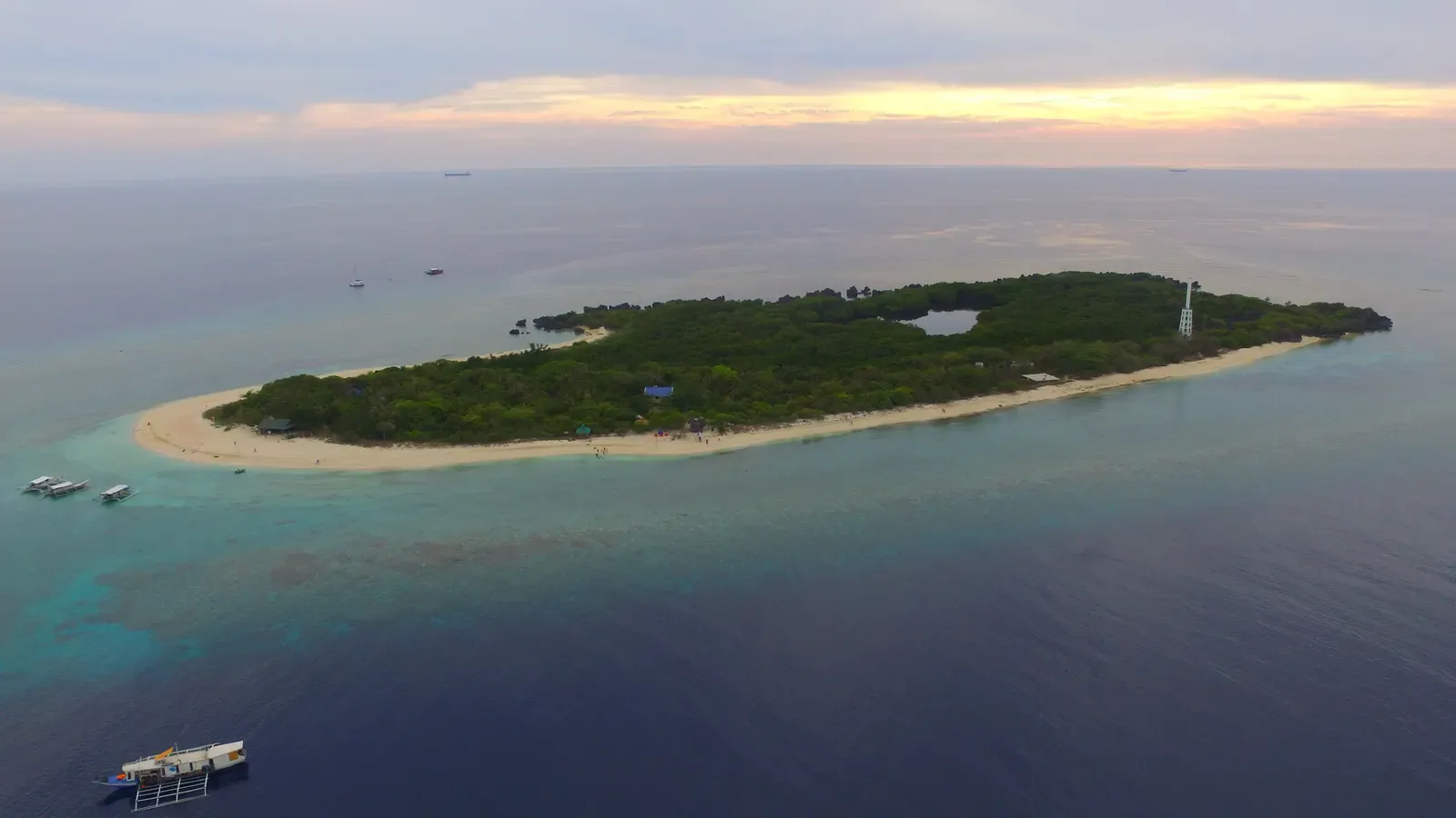 Aerial view of Apo Island's lighthouse islet ringed by reef and lagoon — Apo Reef.