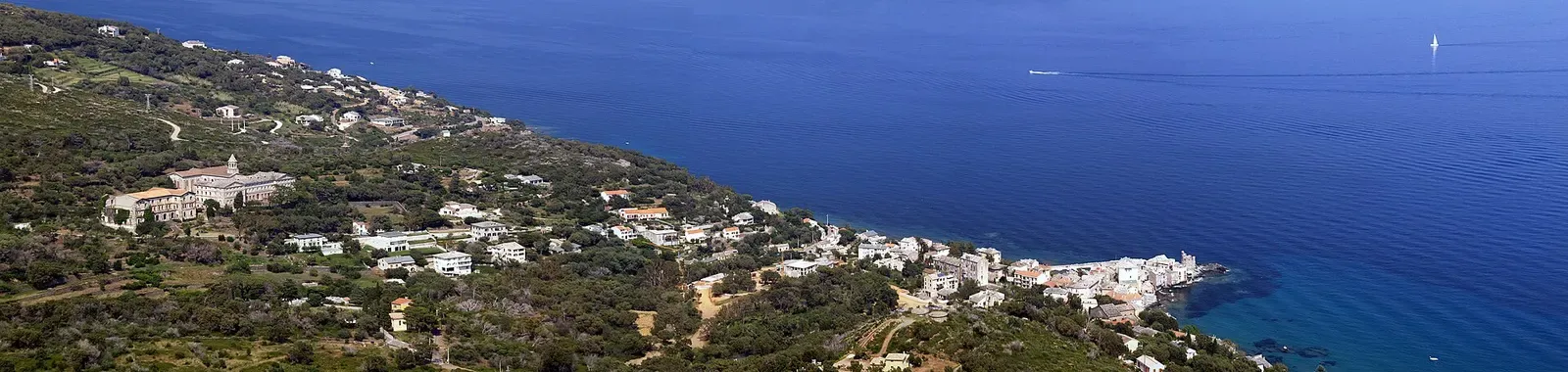 Panorama of Erbalunga's white houses strung along the Mediterranean shoreline