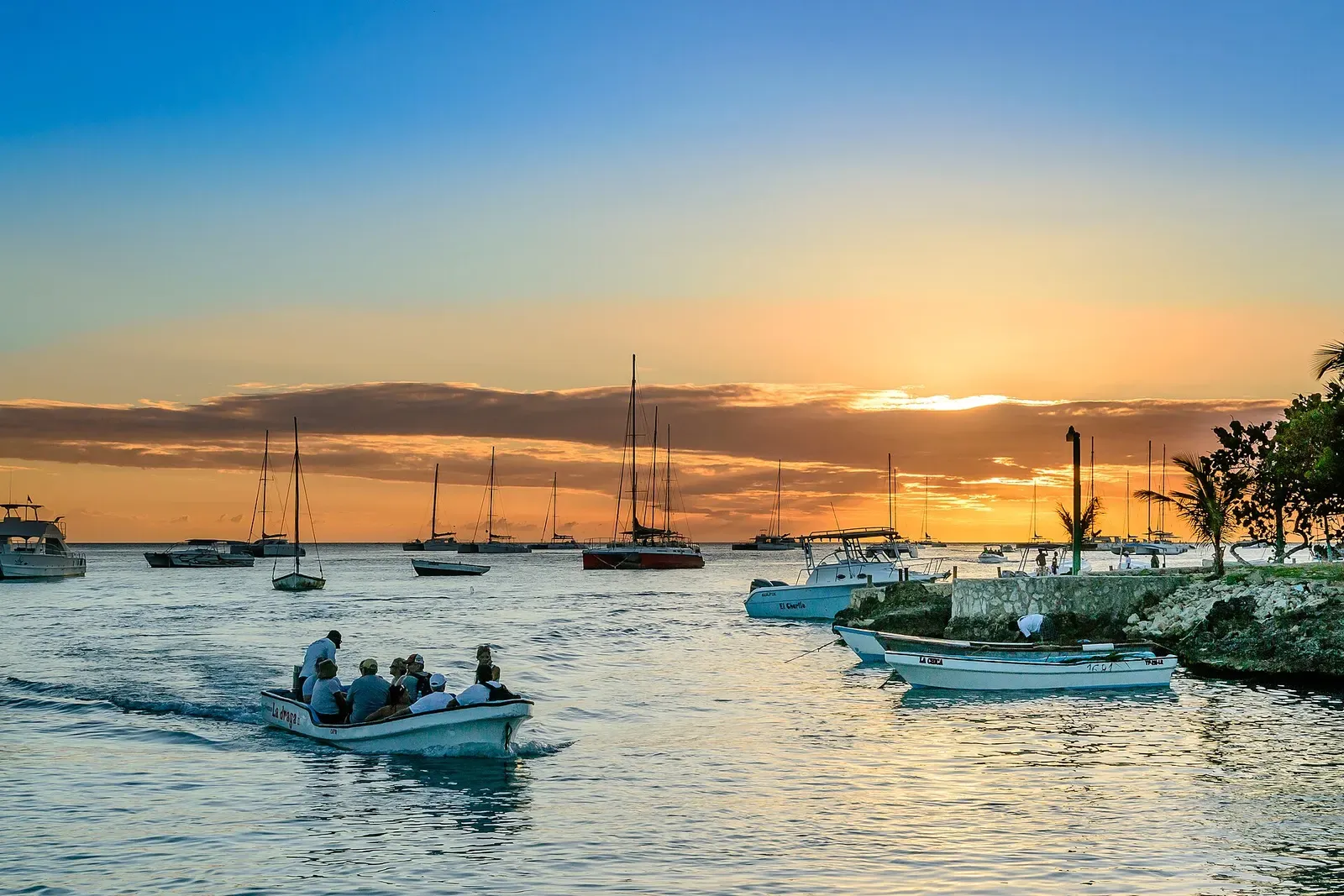 Yachts and small boats moored at sunset with a loaded panga heading out