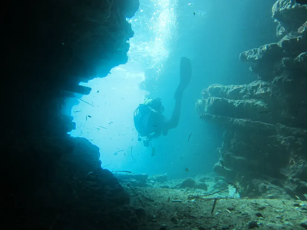 A diver enters a sunlit underwater cavern opening at Peristeres, Corfu.