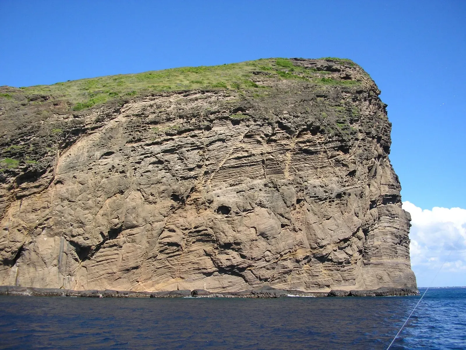 Close view of the layered volcanic rock face of Ile Coin de Mire above the water — Djabeda, Mauritius.