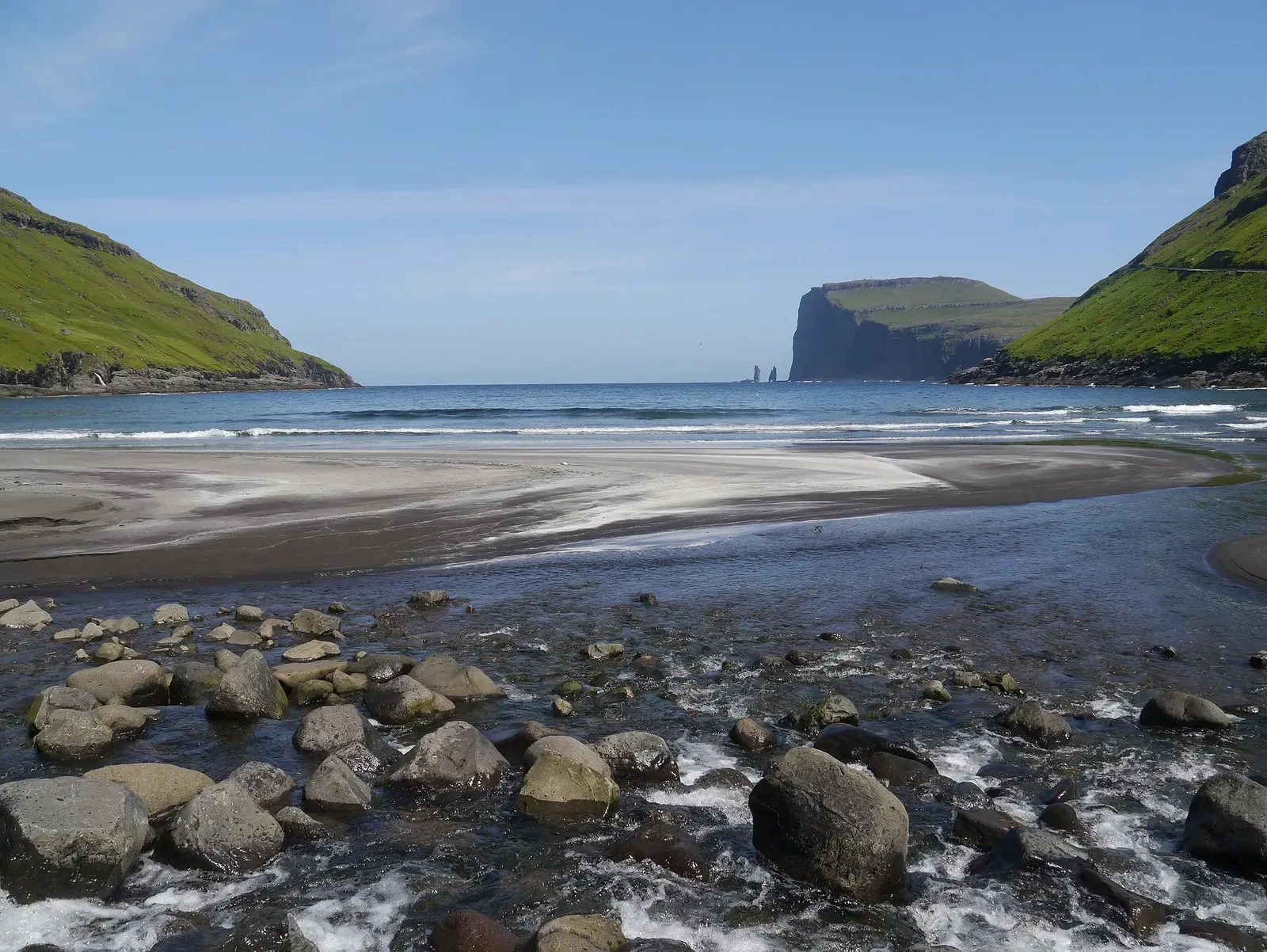 Rocky, stone-strewn beach at Tjørnuvík with a sea stack visible in the distance — Shores at Tjørnuvík, Faroe Islands