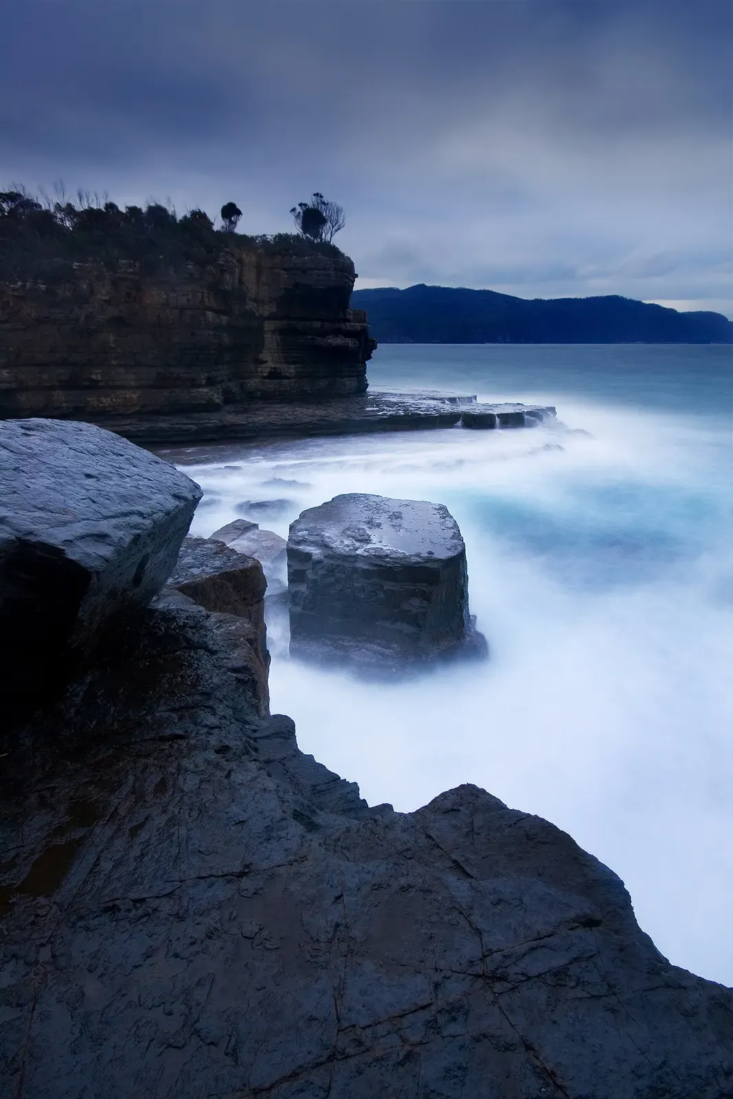 Long-exposure view of mist and sea swirling around rock stacks at Fossil Bay, Tasman Peninsula — Eaglehawk Neck.