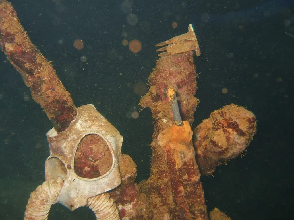 Corroded gas masks and rifles resting inside the Fujikawa Maru wreck — Chuuk Lagoon