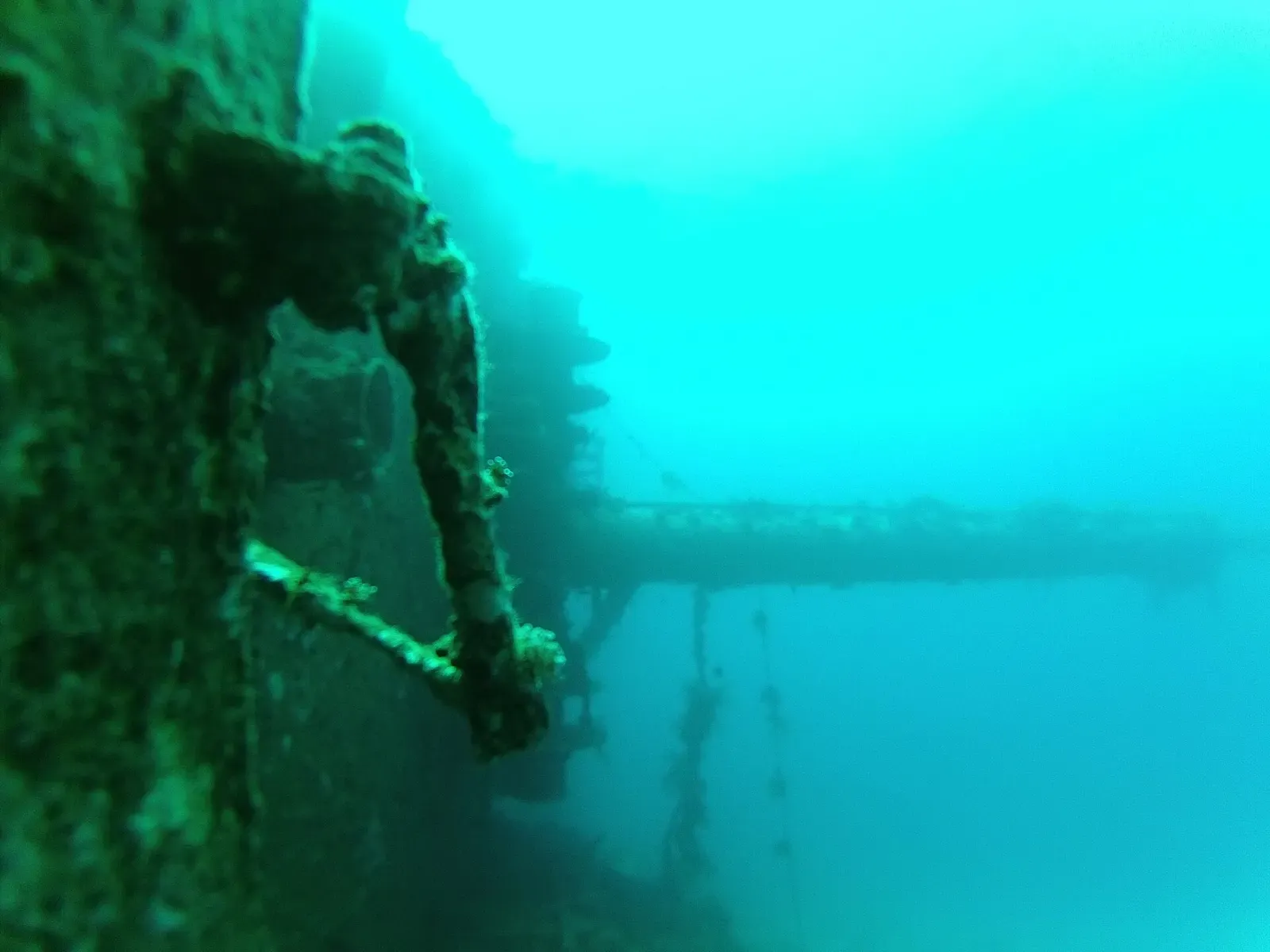 A corroded deck fitting and railing on the Giannis D wreck in green light — Hurghada & El Gouna
