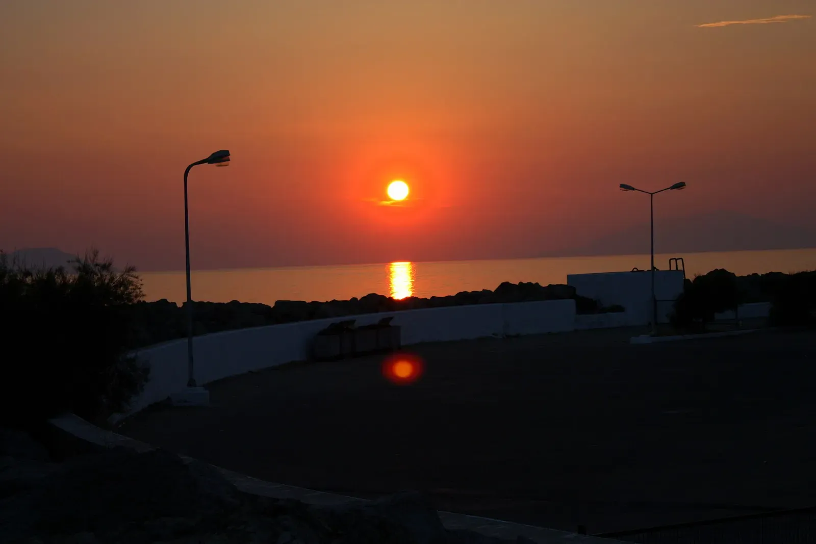 The sun setting into a calm sea beyond a harbour wall at Kabatepe — Gallipoli.