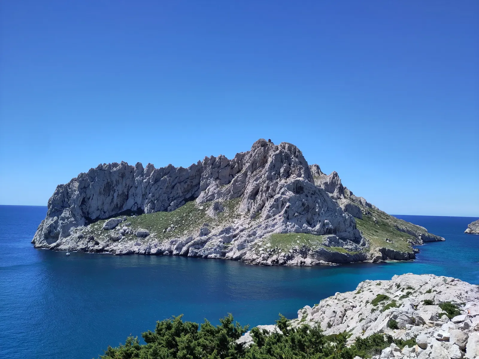 Rugged white limestone ridge of Île Maïre rising from deep blue sea under a clear sky — Marseille