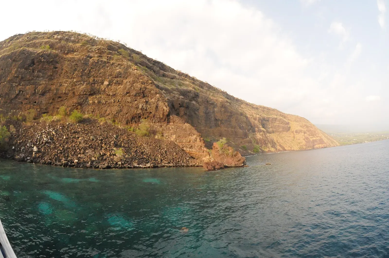 The steep lava cliff above Ka'awaloa Cove rises from the calm water of Kealakekua Bay — Kona.