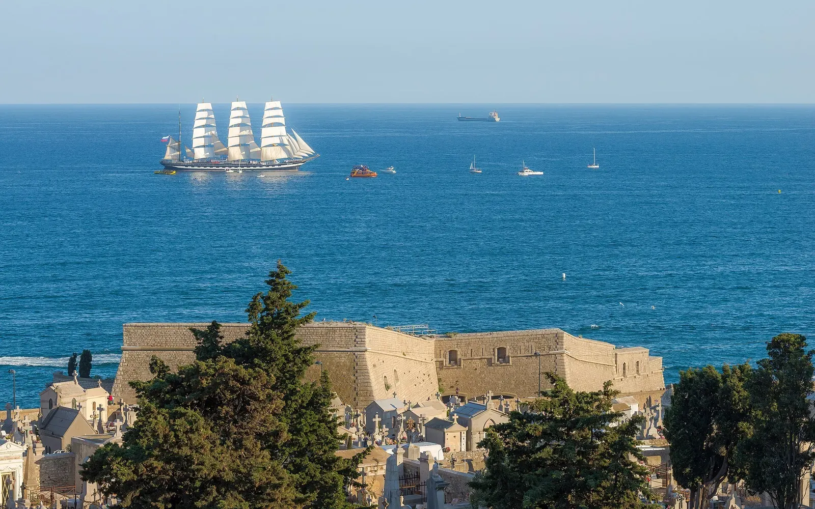 A tall ship under sail passing the Théâtre de la Mer fort on the Sète coastline