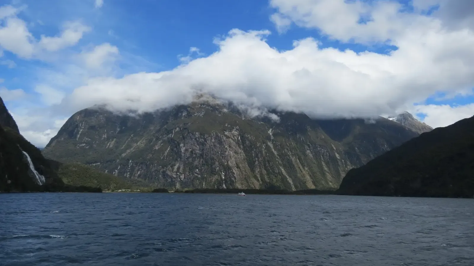 Cloud-wrapped peak reflected in the still waters of Milford Sound — Fiordland