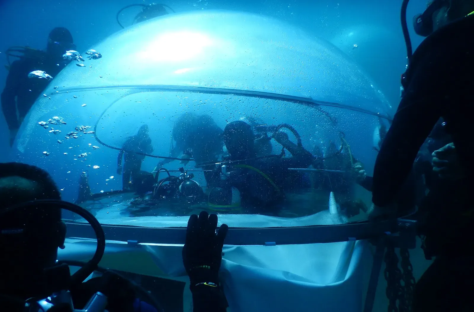 Divers inside a biosphere dome, viewed from within the transparent structure