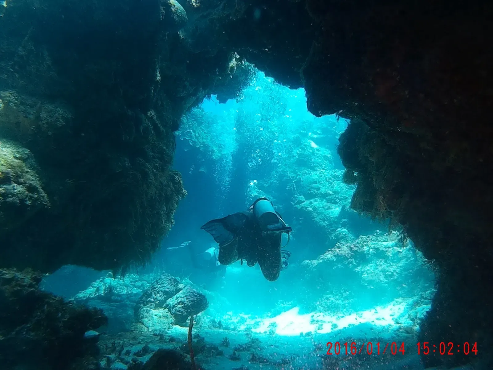 Diver swimming through a sunlit coral archway on Palancar Reef — Palancar Gardens, Cozumel