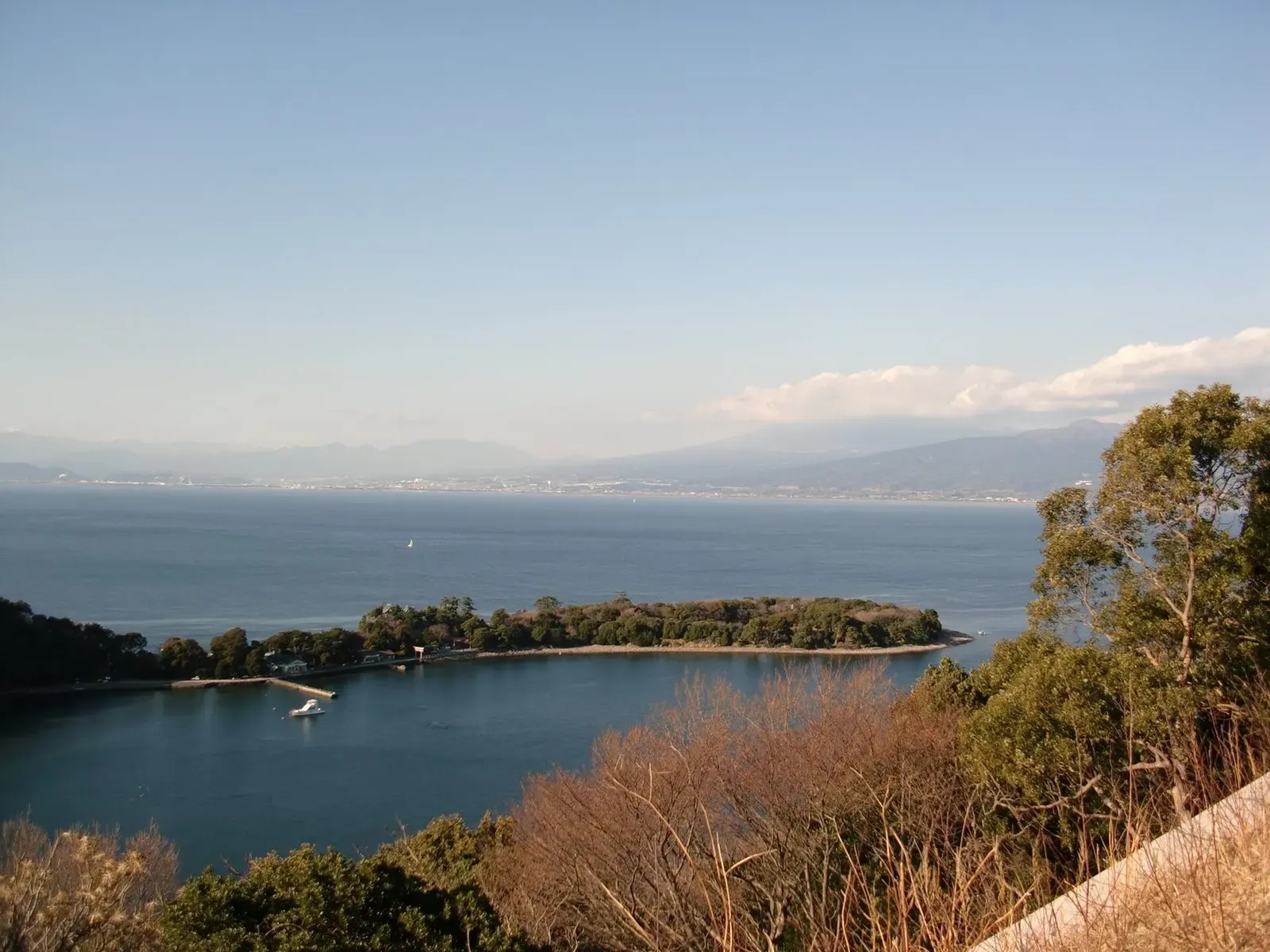 View across Osezaki's sheltered bay toward Mount Fuji with a small boat on the water — Osezaki Bay