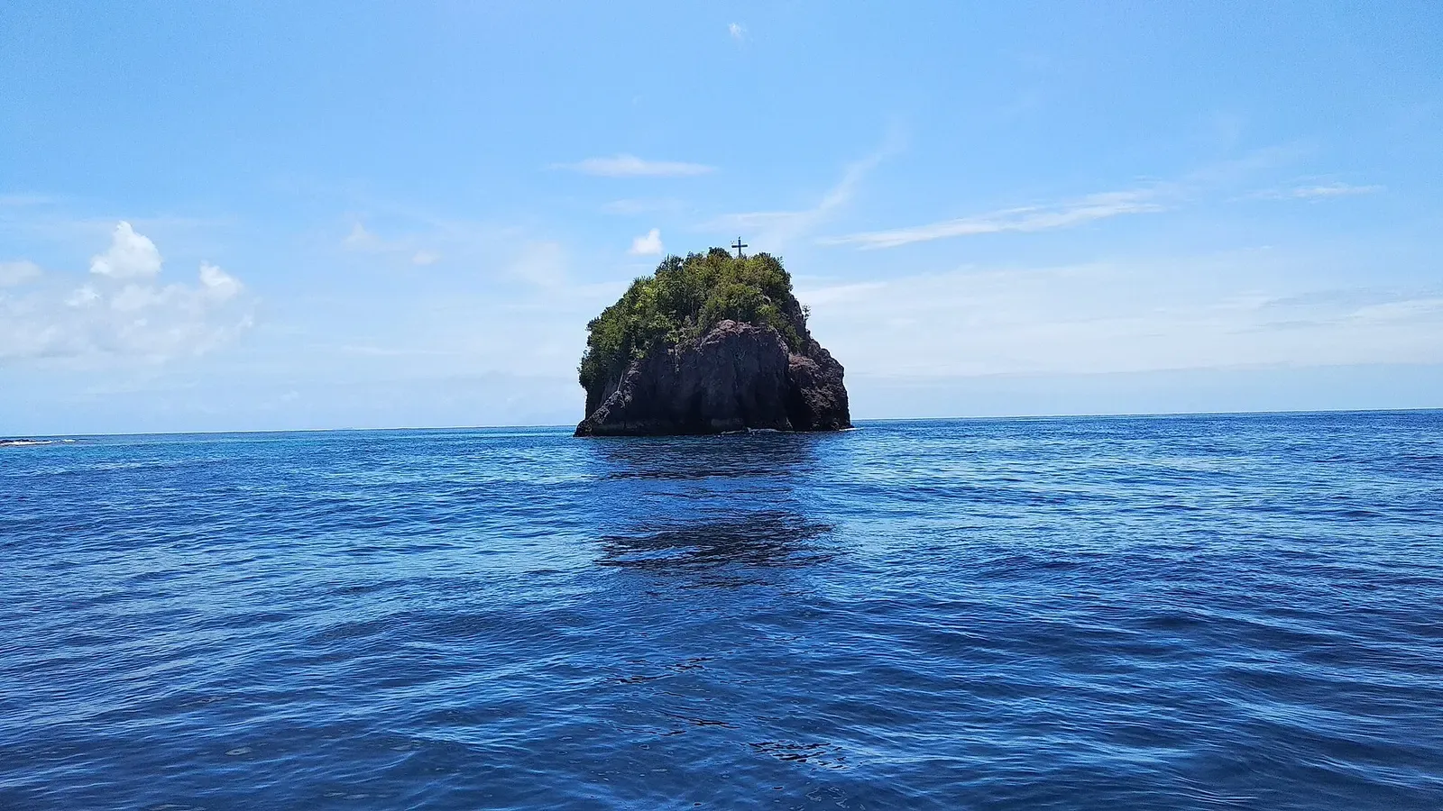 Small uninhabited rock islet rising from deep blue water off Mahengetang — Sangihe