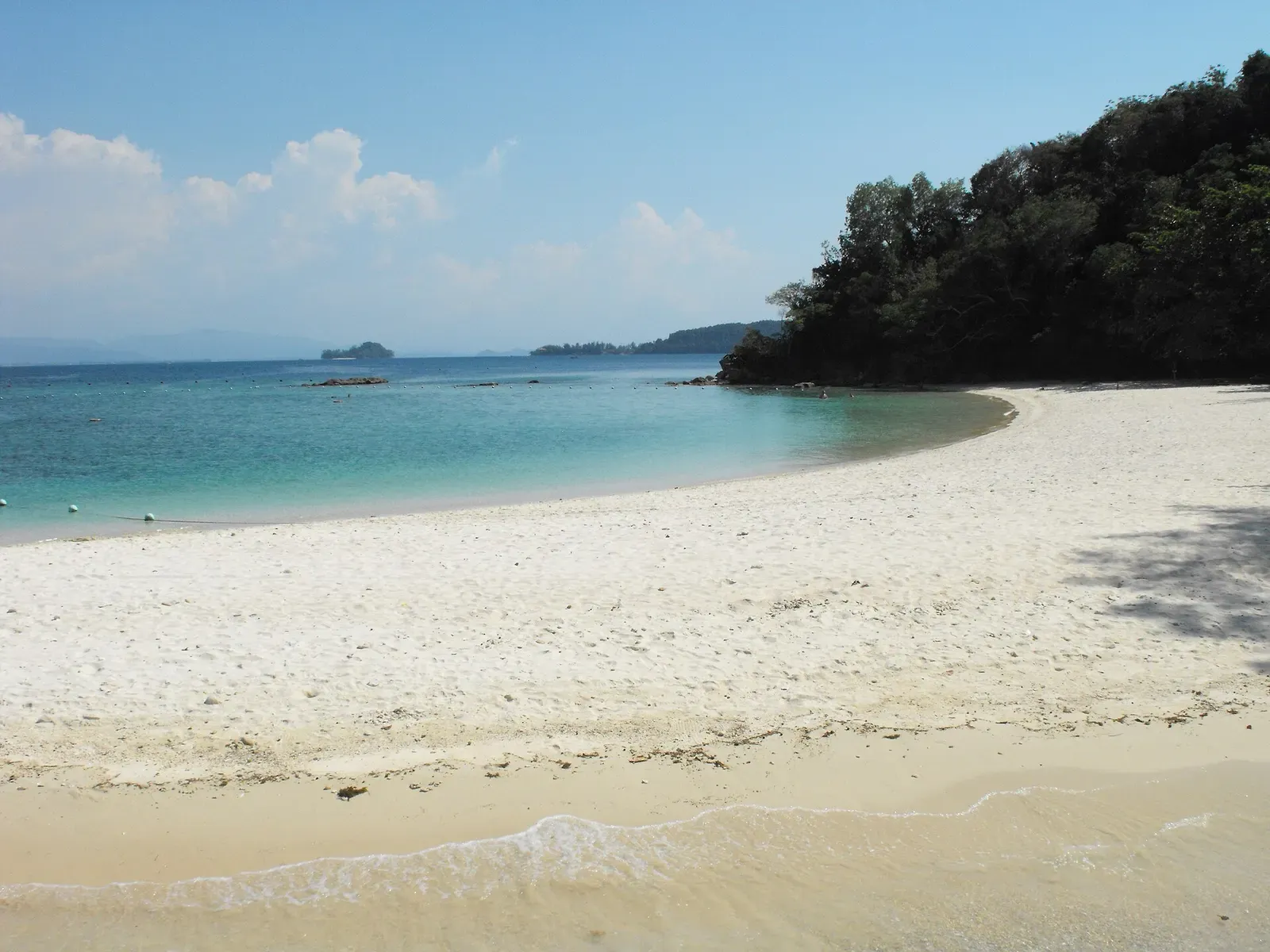 White sand beach curving around a headland on Sapi Island under a blue sky