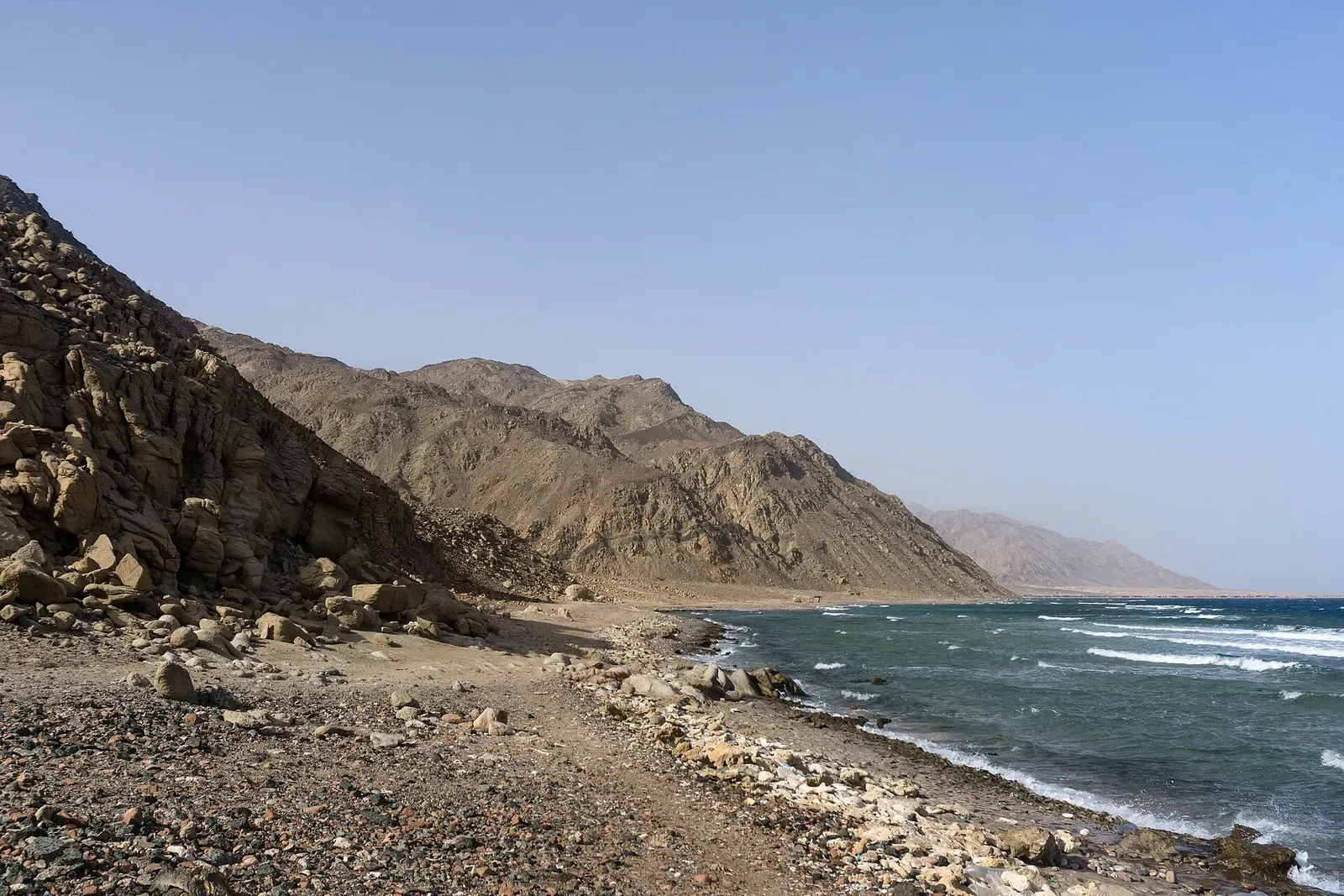 Rocky beach curving along a mountain coastline toward turquoise water — Ras Abu Galum, Dahab