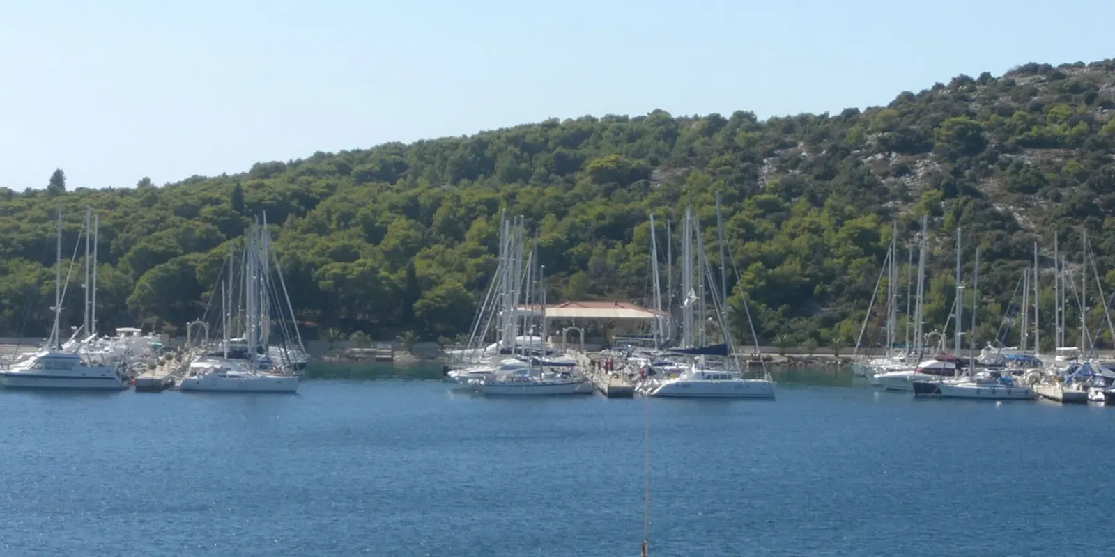Sailboats moored in the bay at Marina Frapa, with a forested peninsula behind.