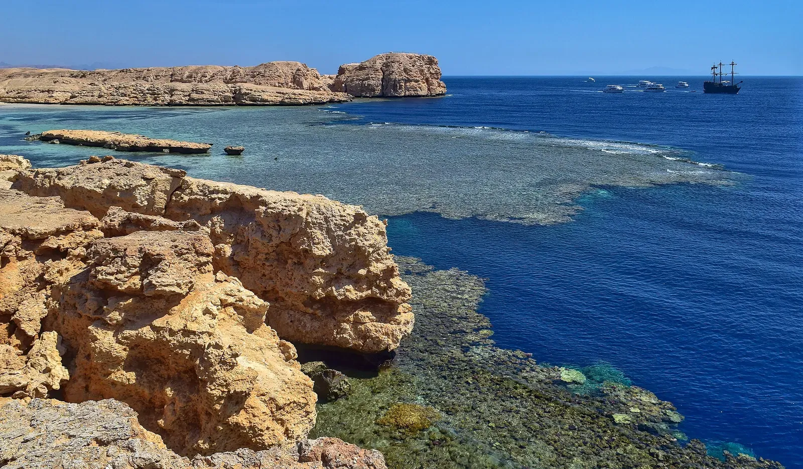 Rocky headland and turquoise inlet at Shark Observatory Bay, the shore point above the reef — Sharm El Sheikh.